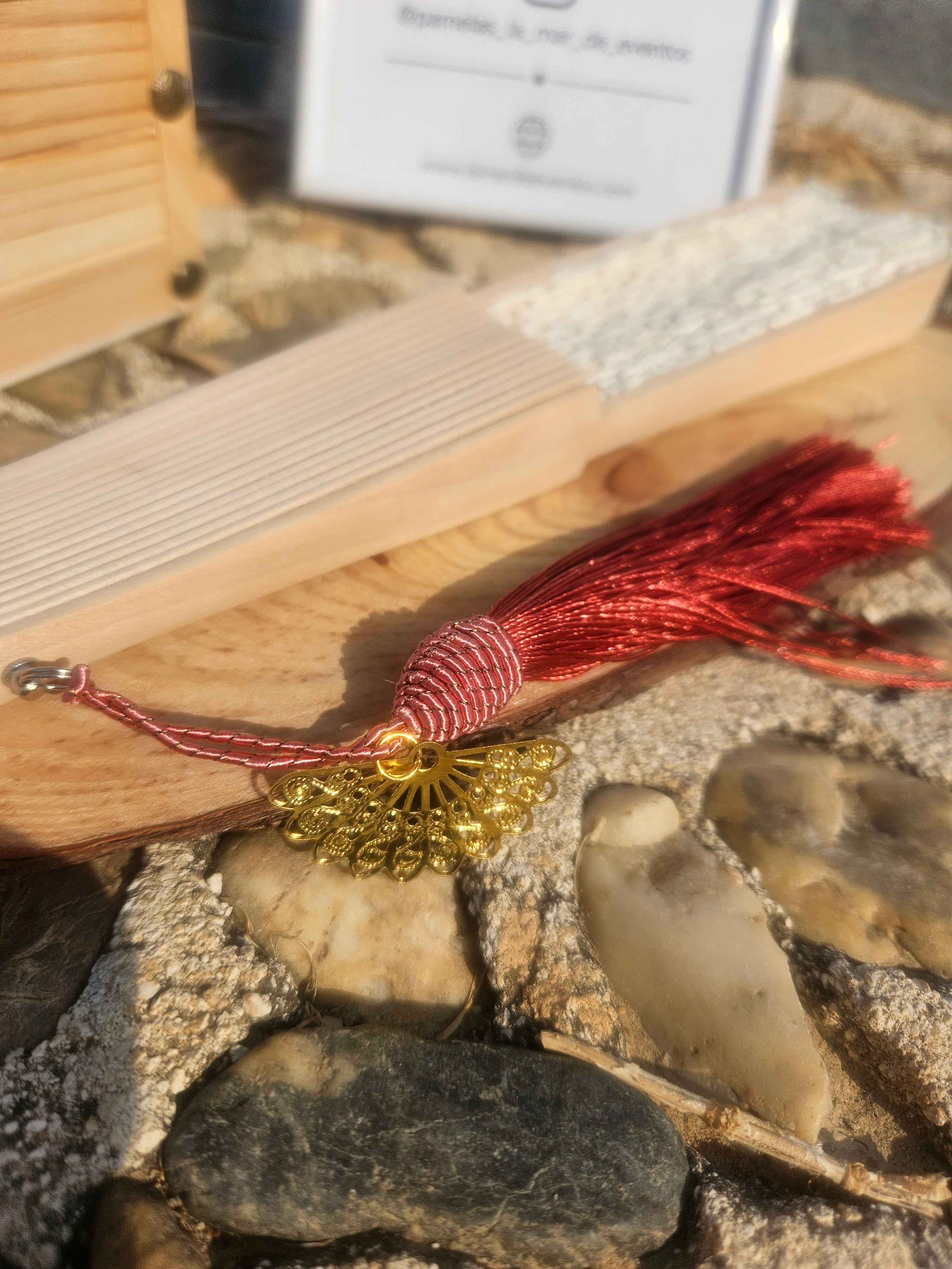 Borla granate y adorno dorado en el extremo de un abanico de madera