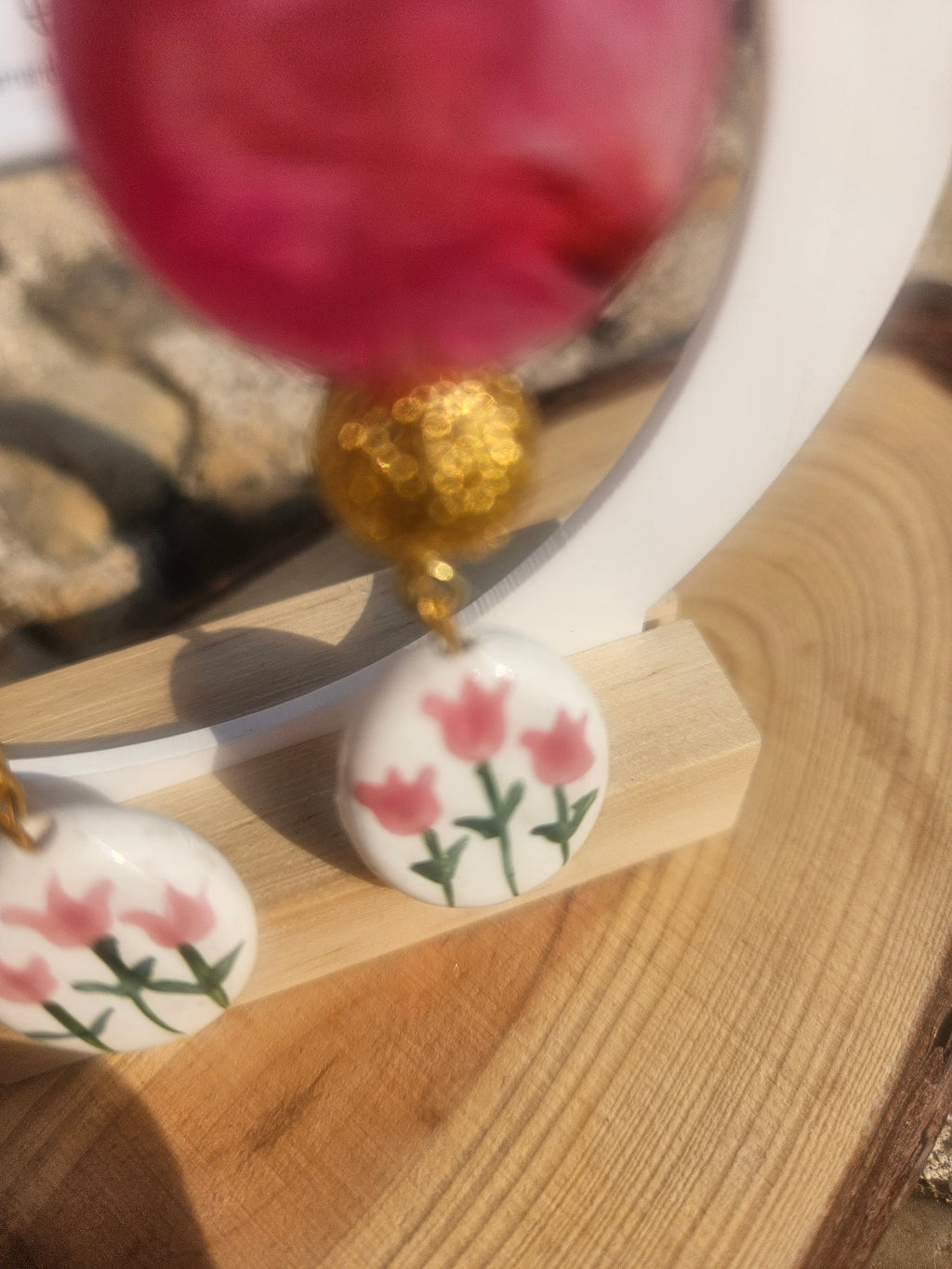 Detalle de pendientes Fiult: cuenta rosa con colgante floral en tonos rosados y verdes