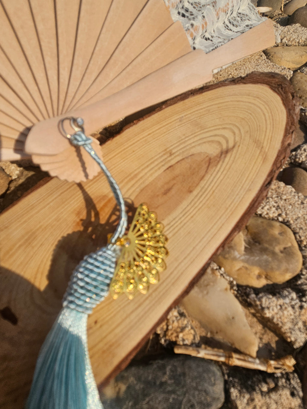 Abanico de madera con borla azul turquesa y detalle dorado en el cordón