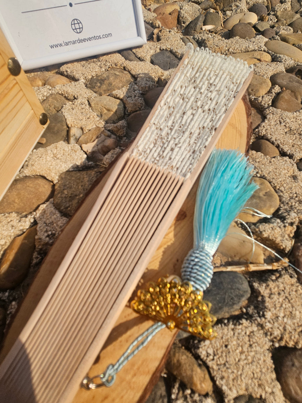 Abanico de madera con cordón y borla turquesa, con detalle dorado en la anilla