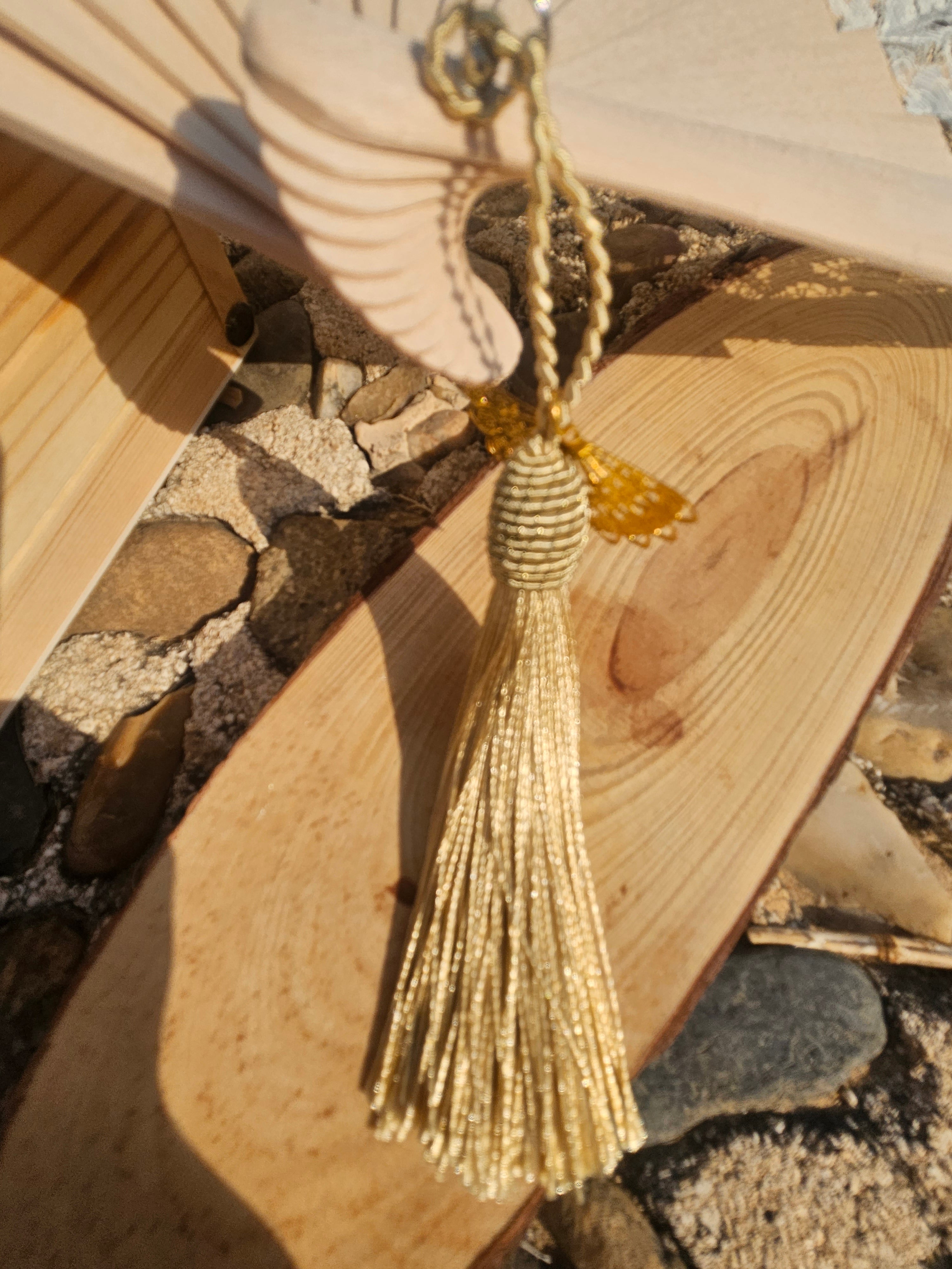 Abanico beige con encaje blanco y borlas doradas; detalle de la cuerda