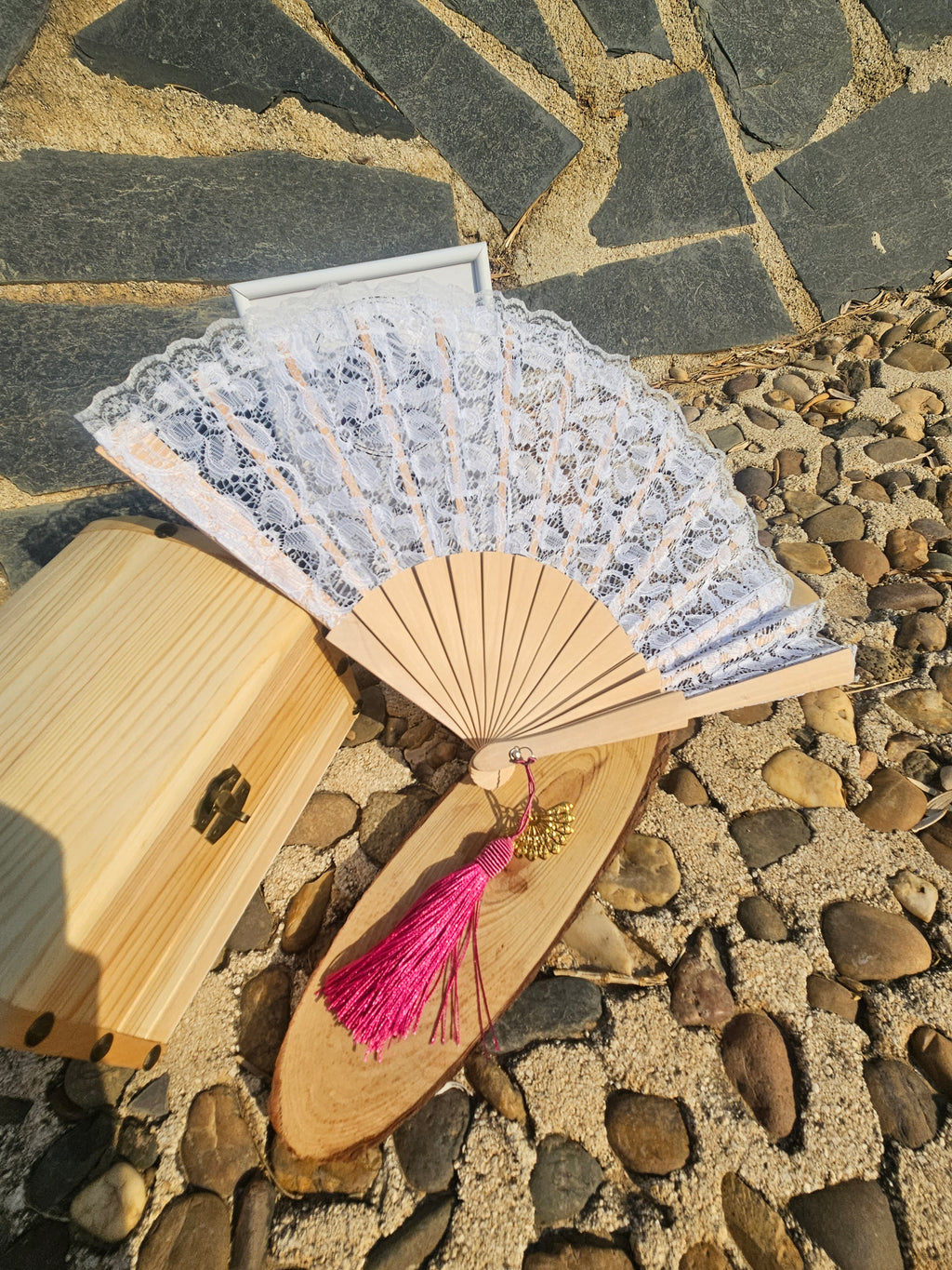 Abanico con encaje blanco y varillas de madera, borla fucsia colgante y adorno dorado
