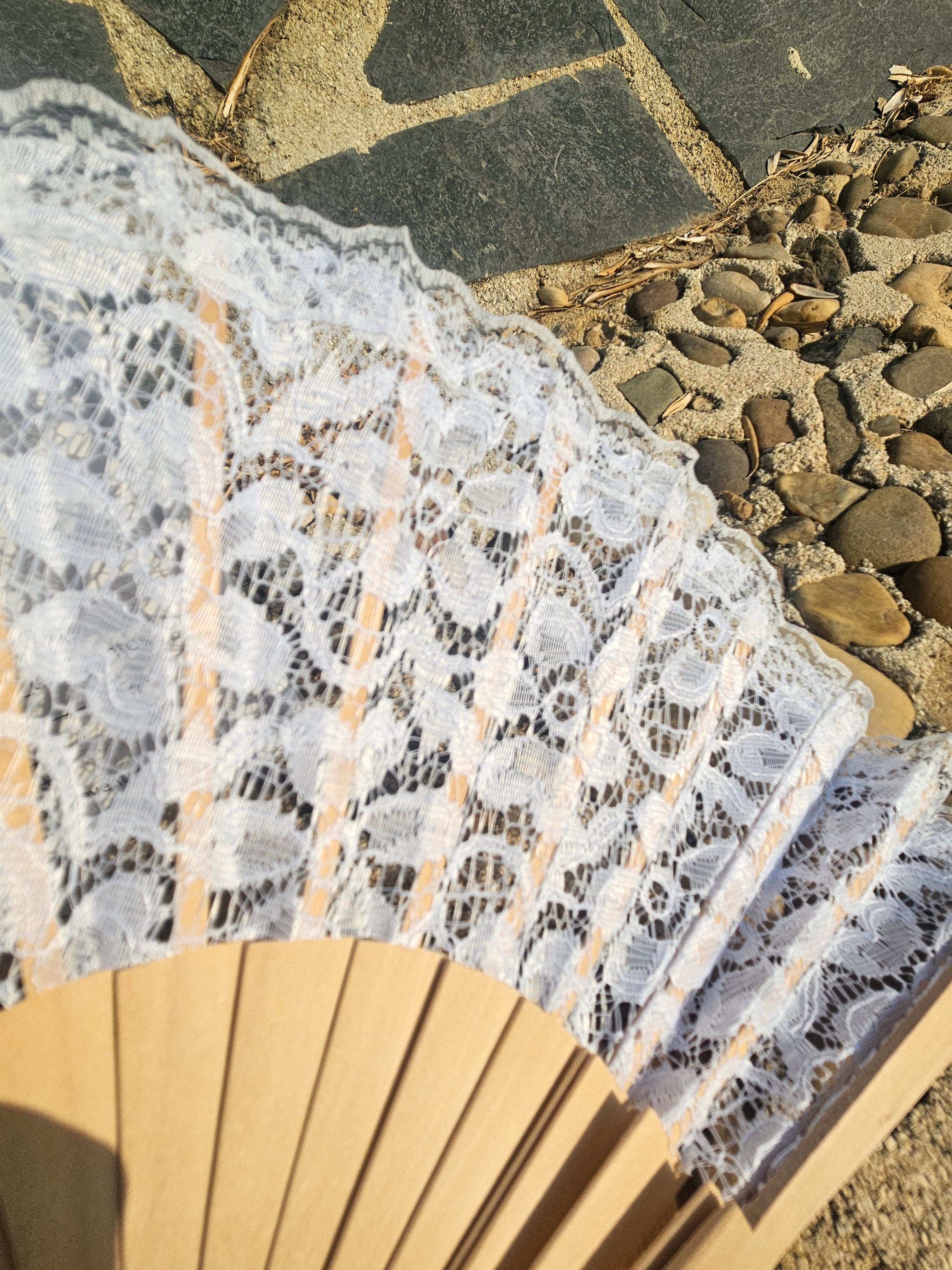 Detalle del abanico: encaje blanco con borde ondulado y varillas de madera visibles