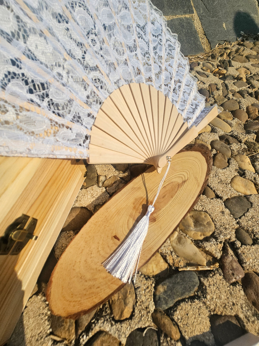 Abanico blanco de madera con encaje y borla plateada colgante.