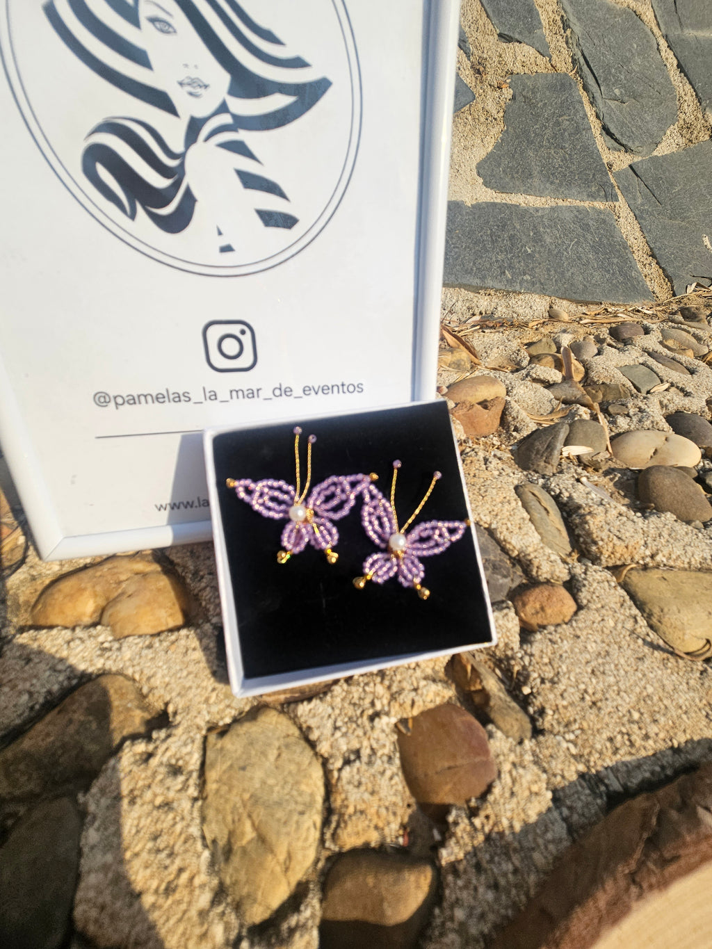Pendientes con mariposas moradas de abalorios y perla, sobre estuche negro