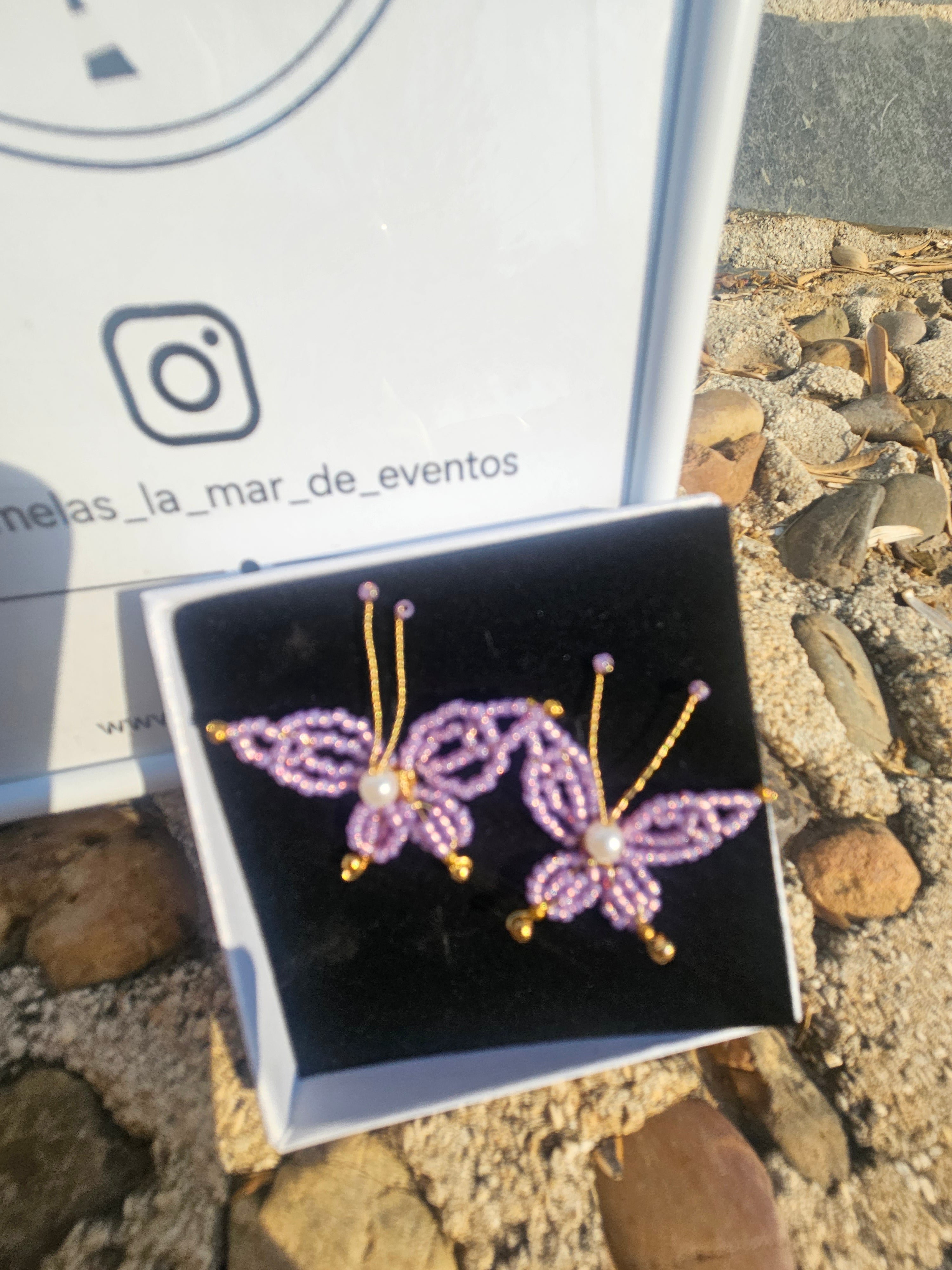 Pendientes con mariposas moradas de abalorios y perla, vistos desde el frente