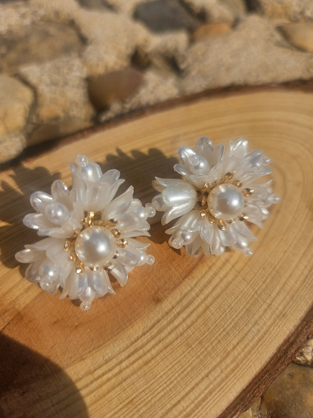 Pendientes florales blancos con perla central y baño dorado, diseño de pétalos