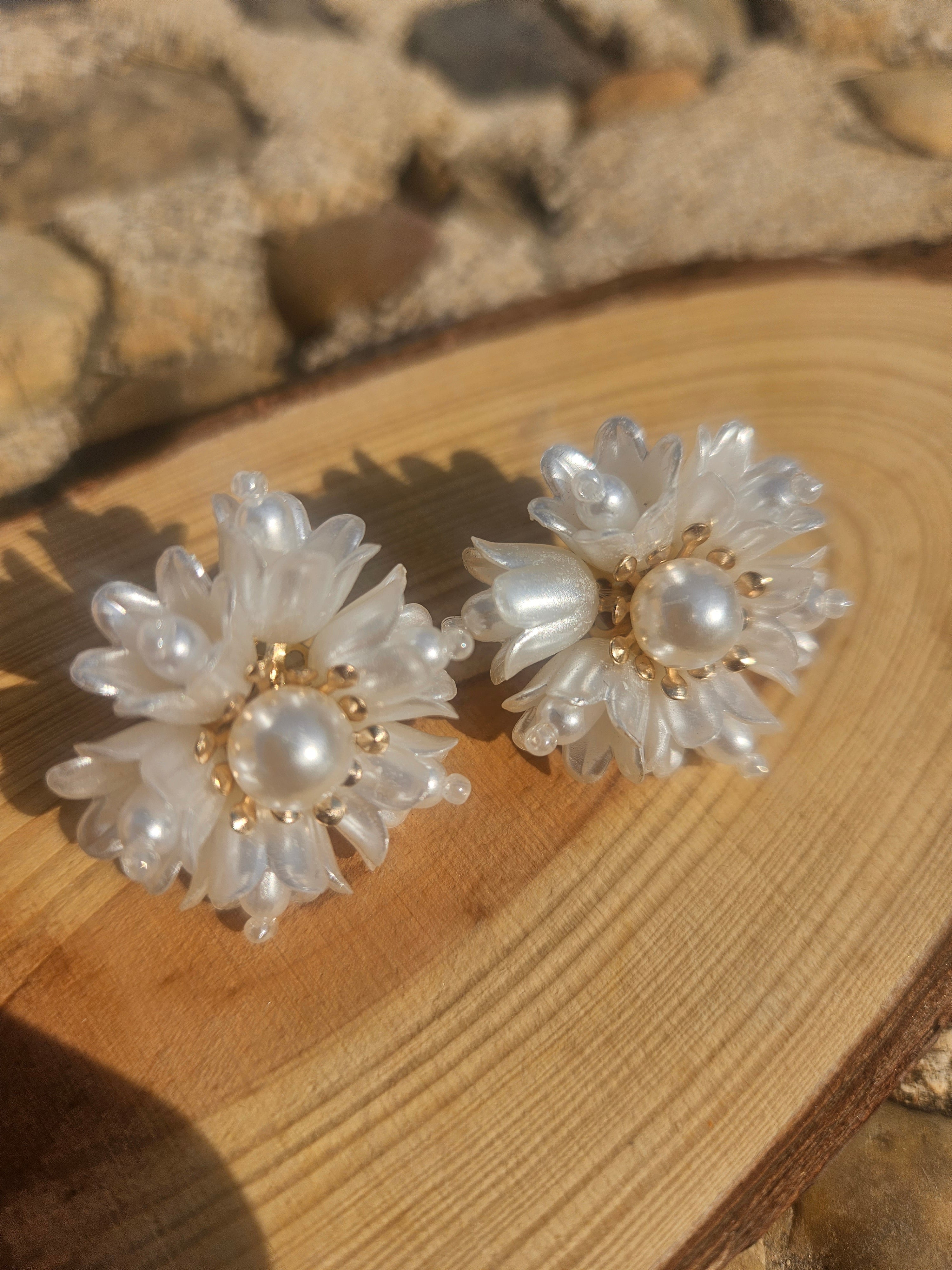 Pendientes florales blancos con perla central y baño dorado, diseño de pétalos