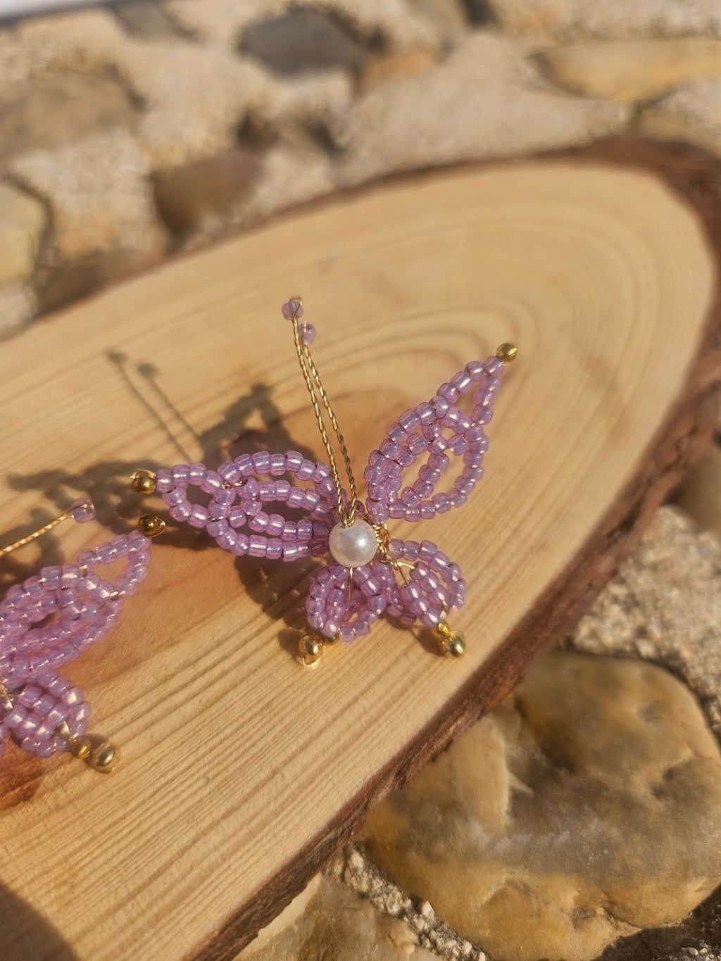 Pendiente con mariposa morada de abalorios y perla, con gancho dorado