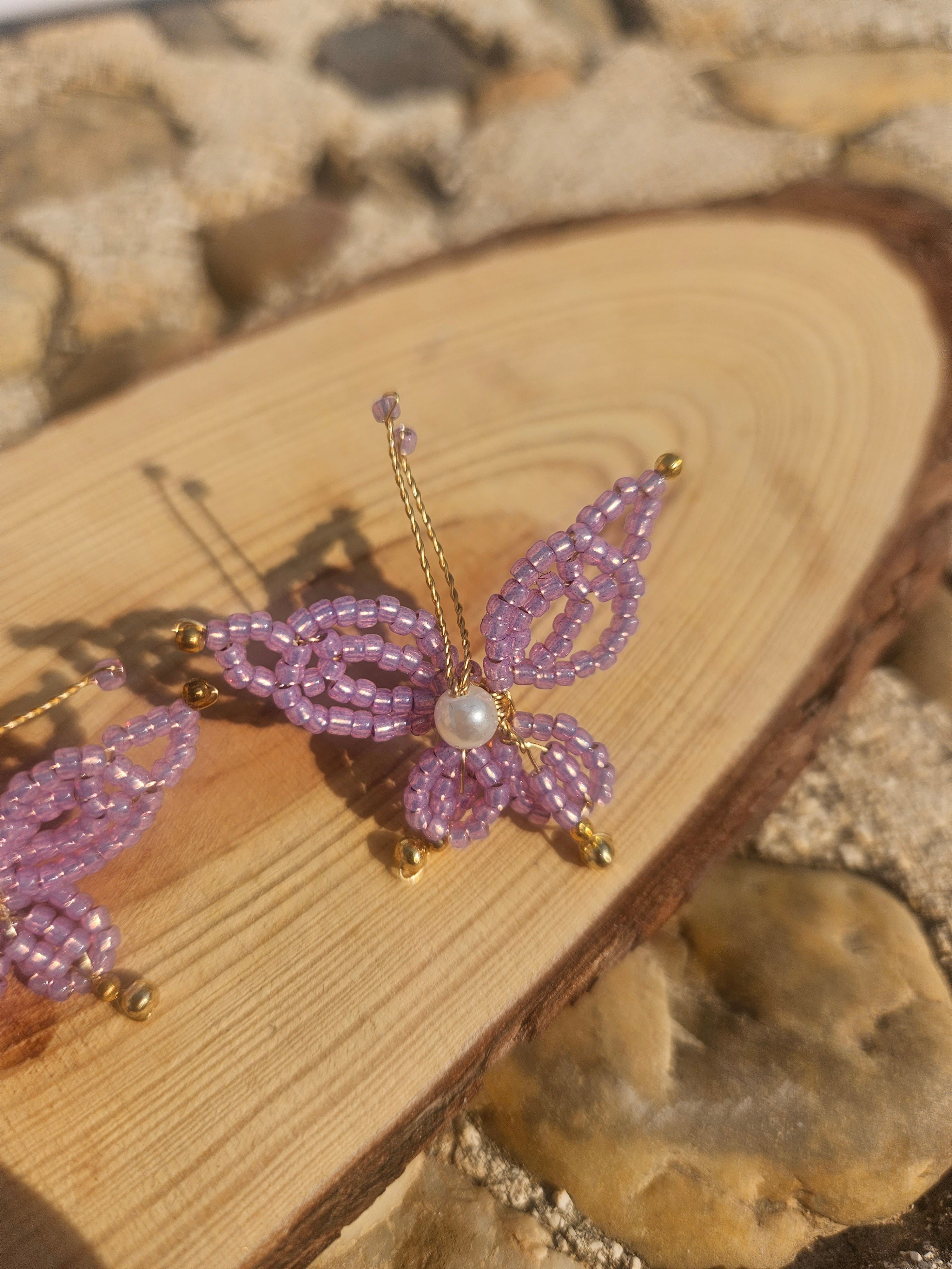 Pendiente con mariposa morada de abalorios y perla, con gancho dorado