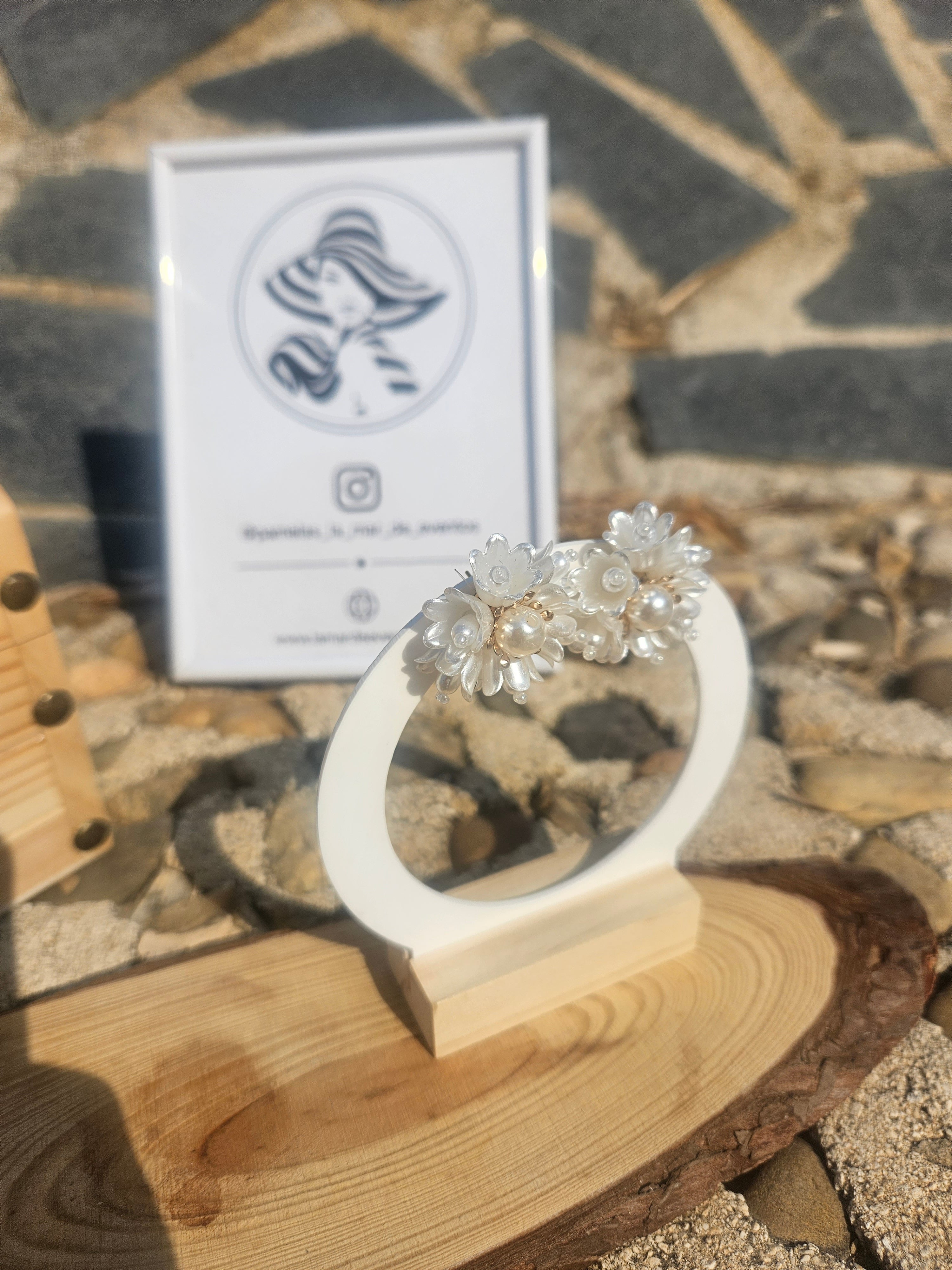 Pendientes florales blancos con perla central y detalles dorados, vista lateral