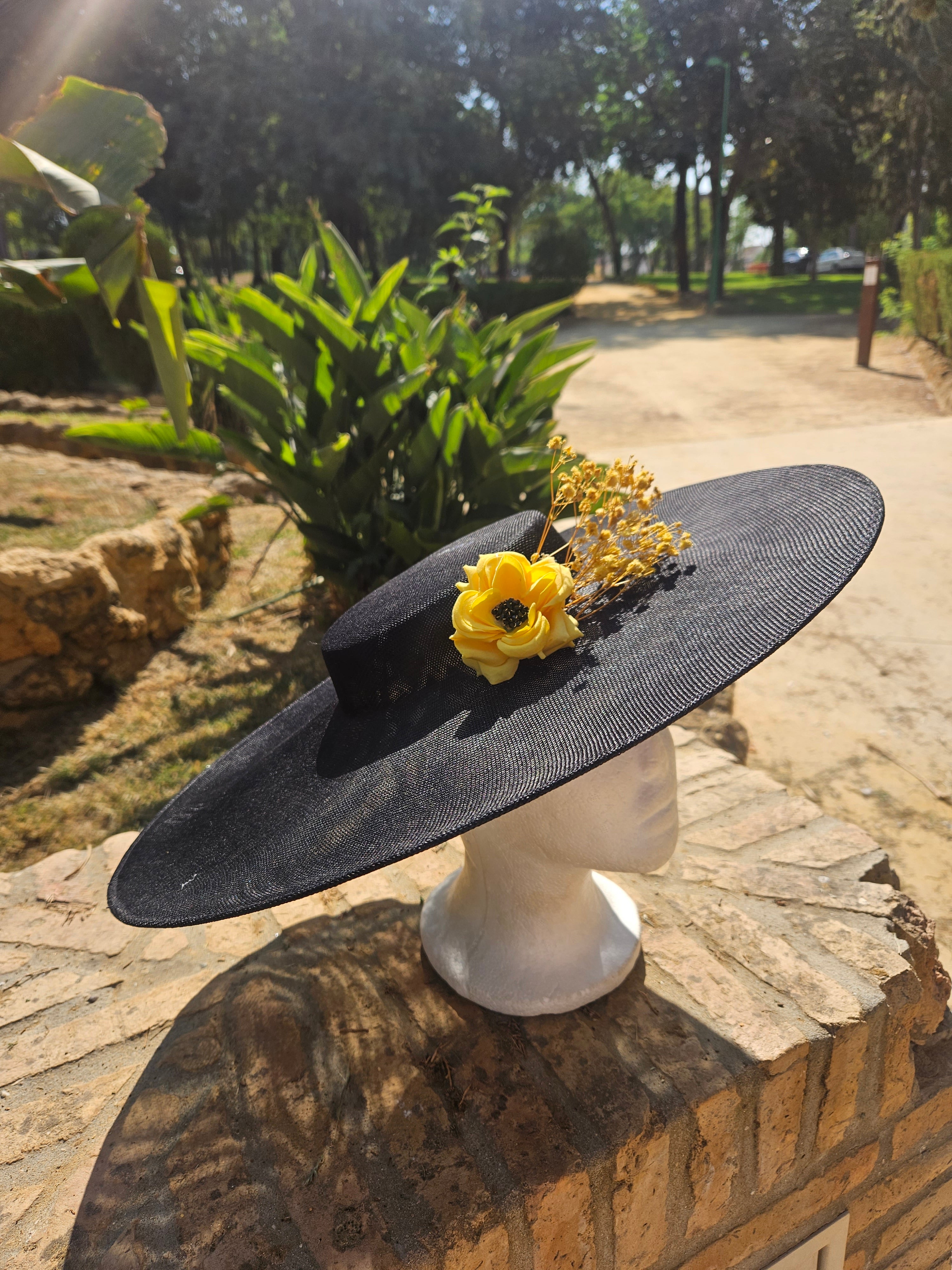 Sombrero de ala ancha negro con flor amarilla y ramo dorado, vista trasera.