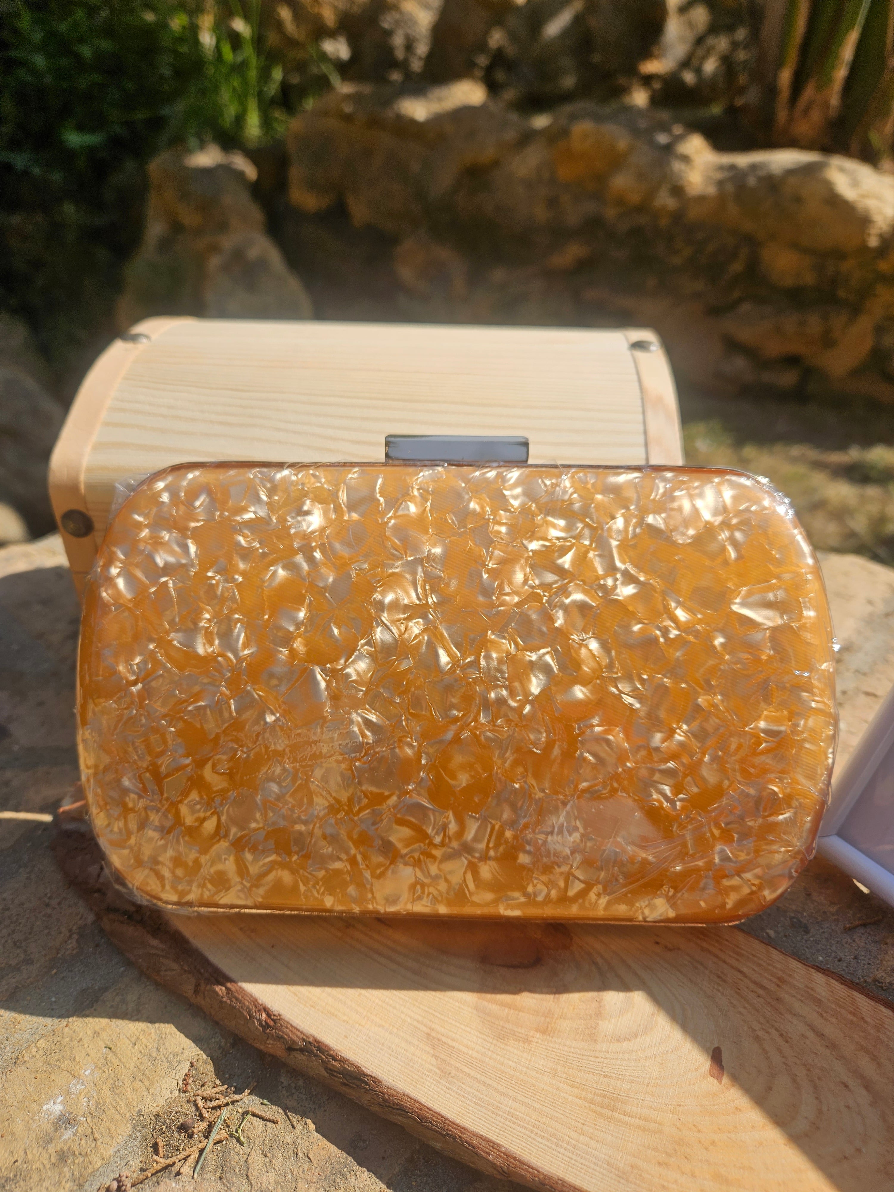 Bolso tipo clutch ámbar con textura efecto piel y cierre superior metálico