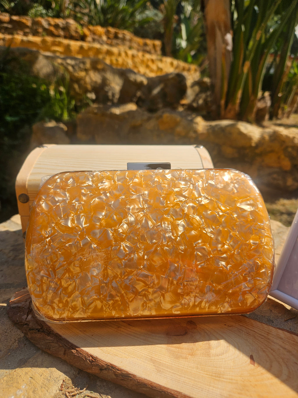 Bolso clutch ámbar con cierre metálico y marco de madera claro