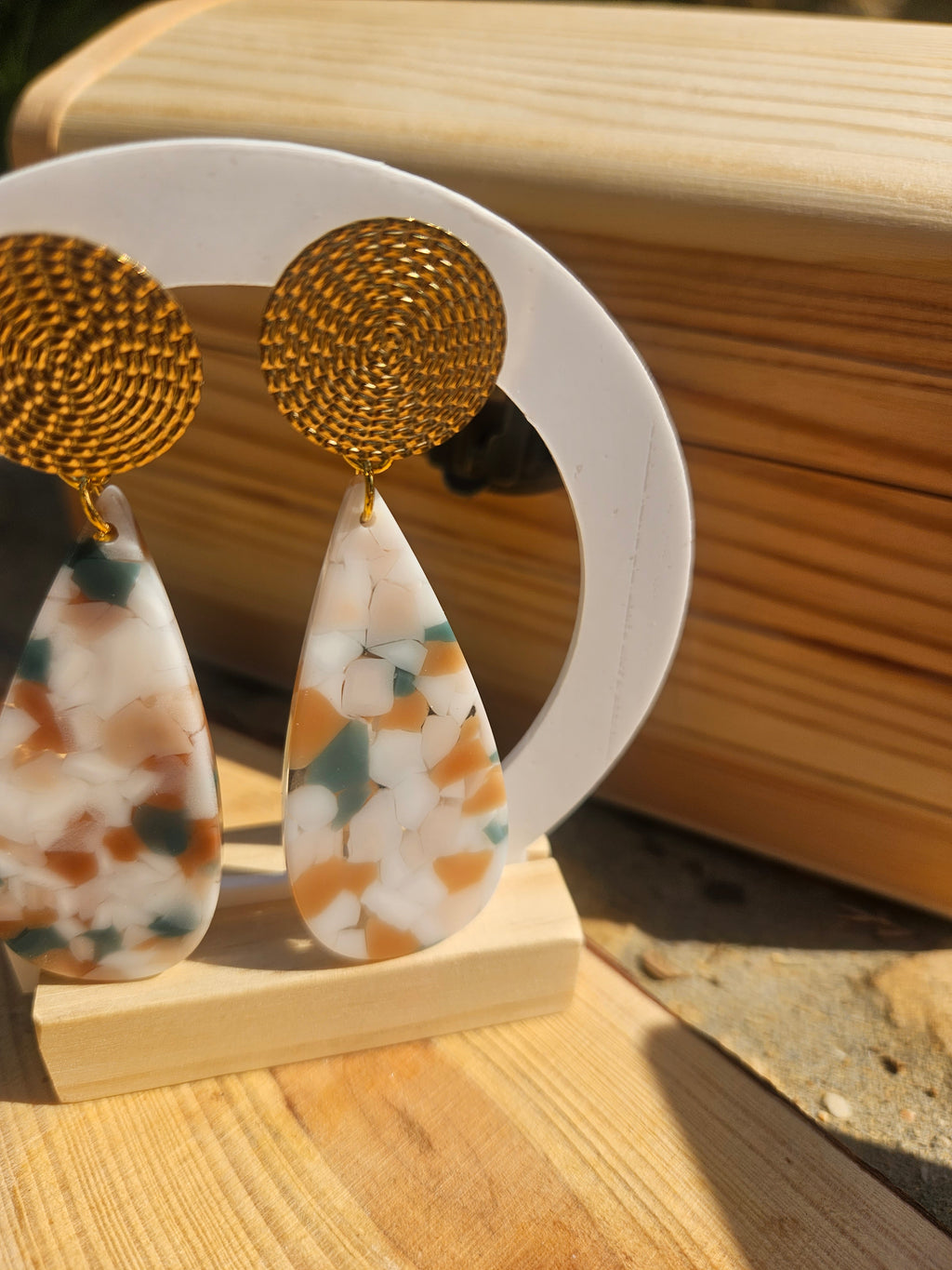 Pendientes colgantes: disco dorado y lágrima de resina con tonos verdes, azules y naranja