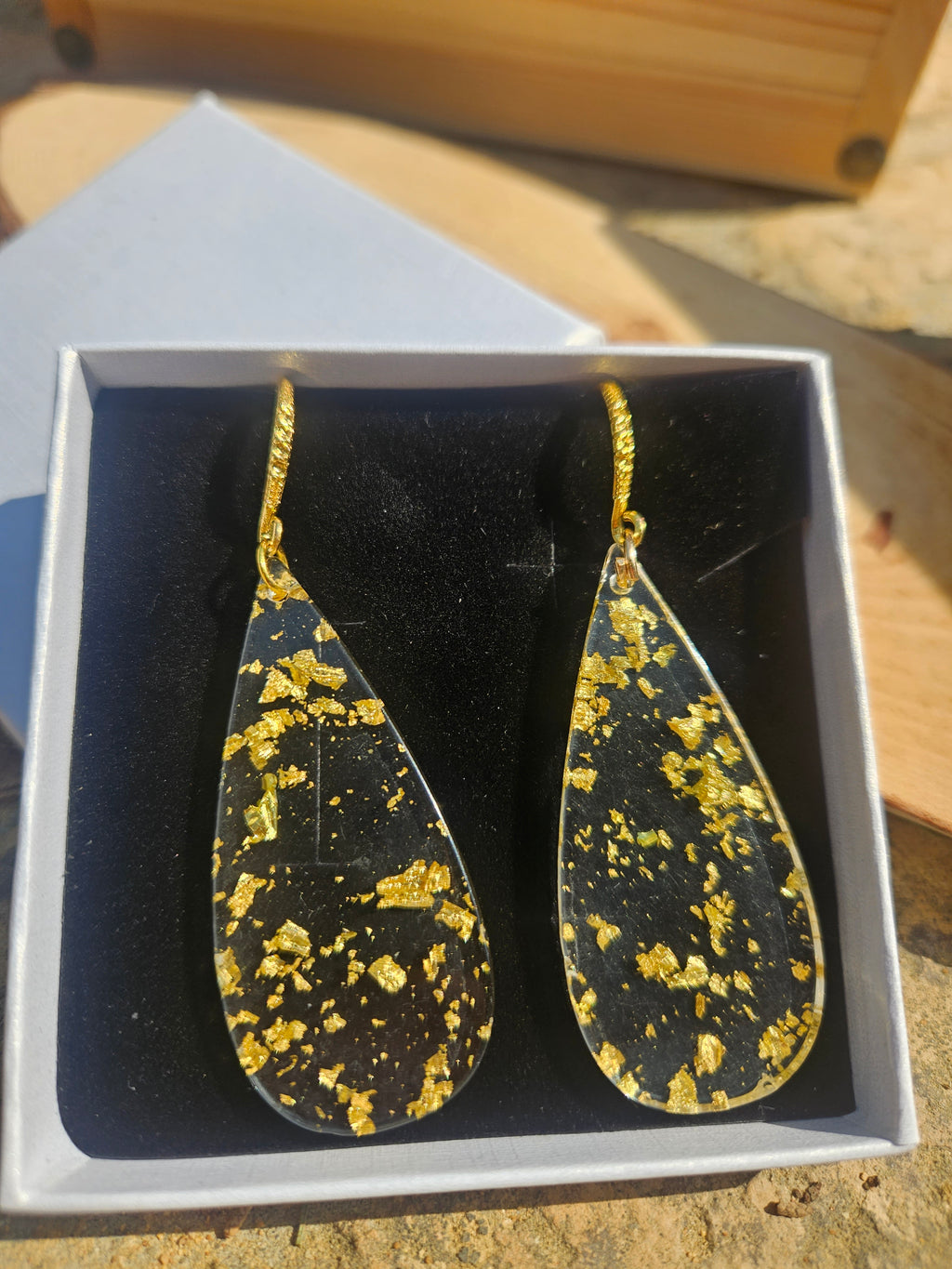 Pendientes de gota dorados con salpicaduras amarillas y gancho, en caja.