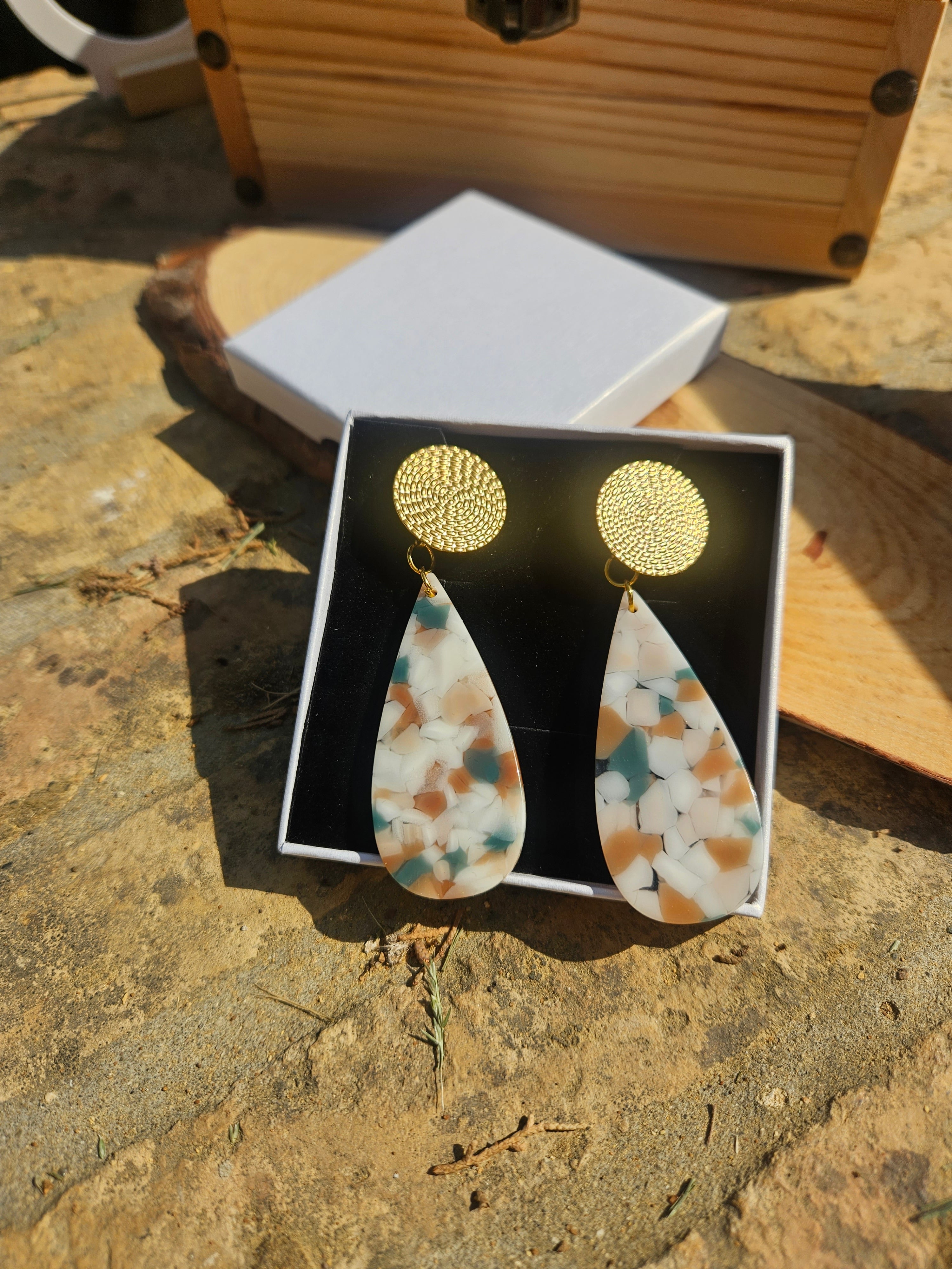 Pendientes en caja abierta con discos dorados y colgantes lágrima de resina multicolor