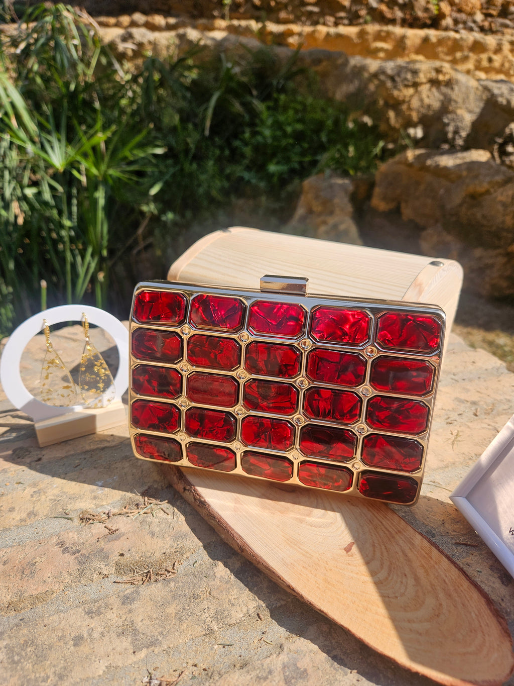 Bolso tipo caja de madera clara con broche superior y panel rojo geométrico