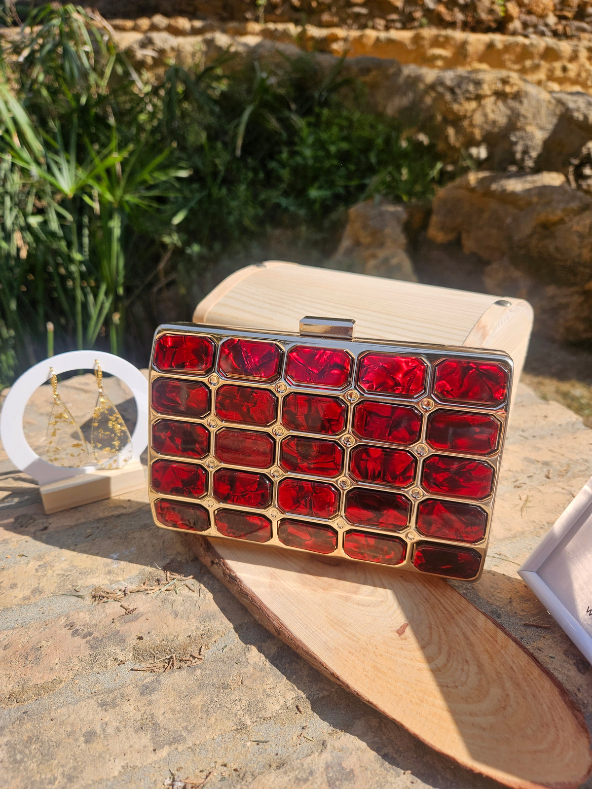 Bolso tipo caja de madera clara con broche superior y panel rojo geométrico
