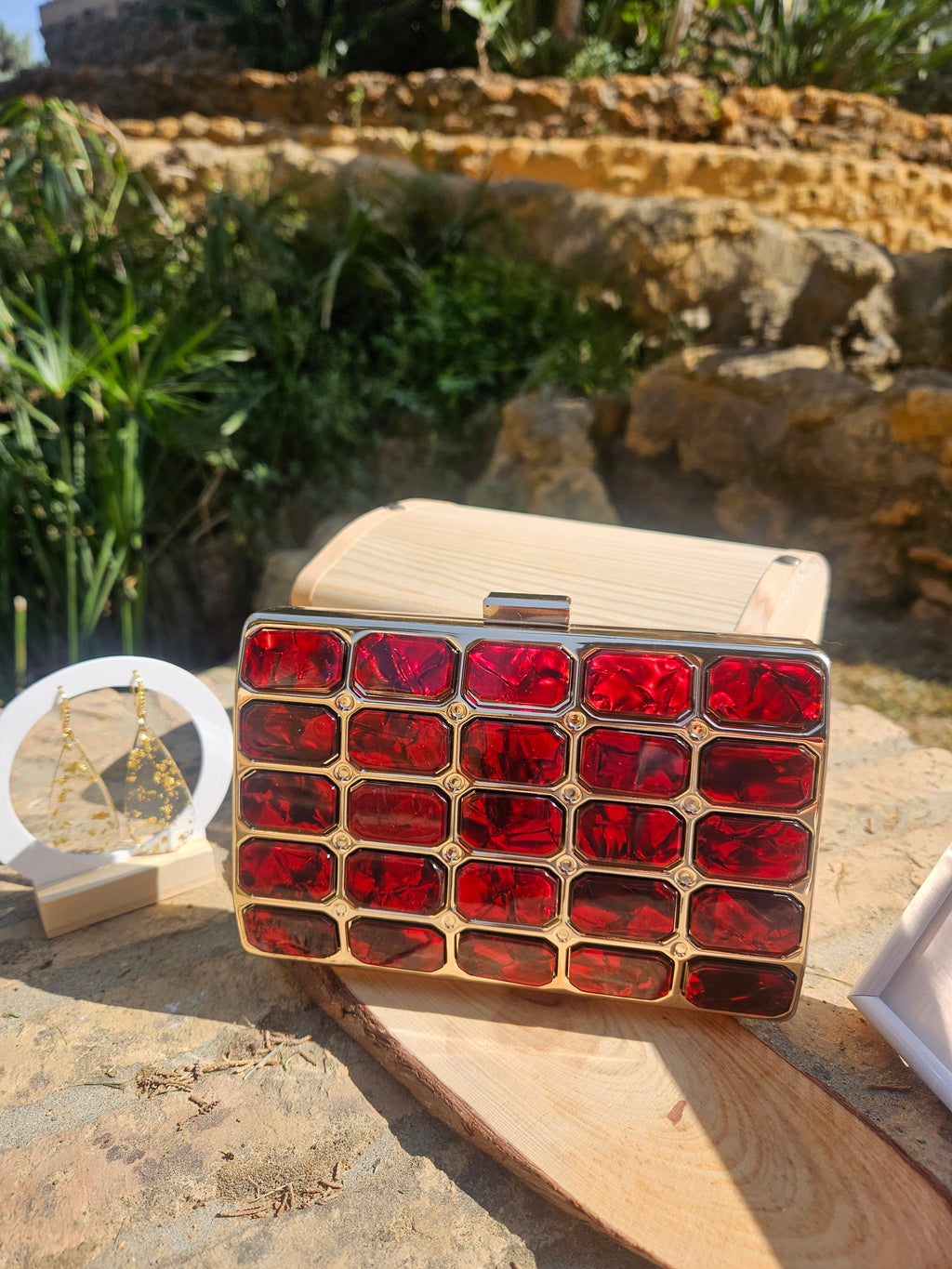 Bolso tipo caja de madera clara con panel rojo cuadriculado y broche metálico superior