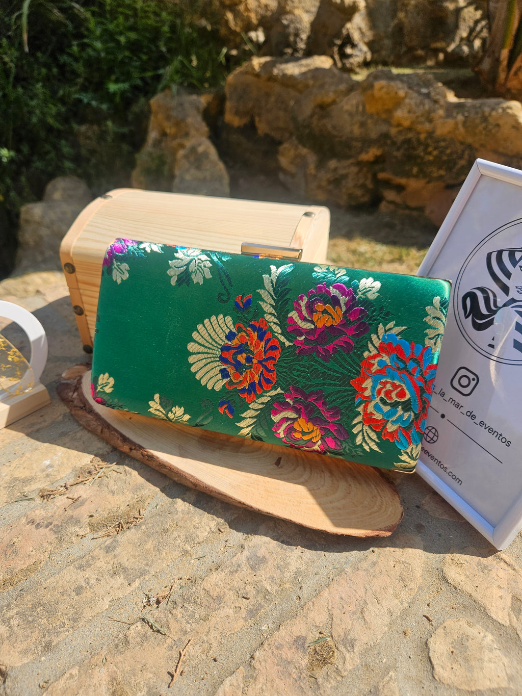 Bolso de mano verde con estampado floral multicolor y cierre metálico en marco de madera