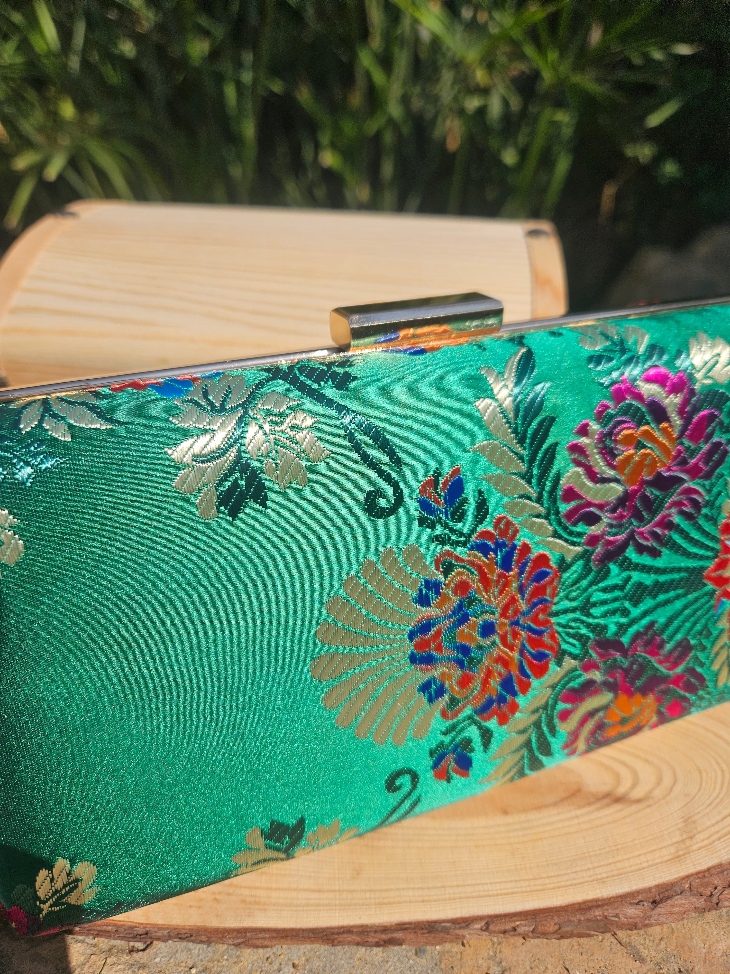 Bolso de mano verde con flores bordadas multicolor en la parte frontal y marco de madera