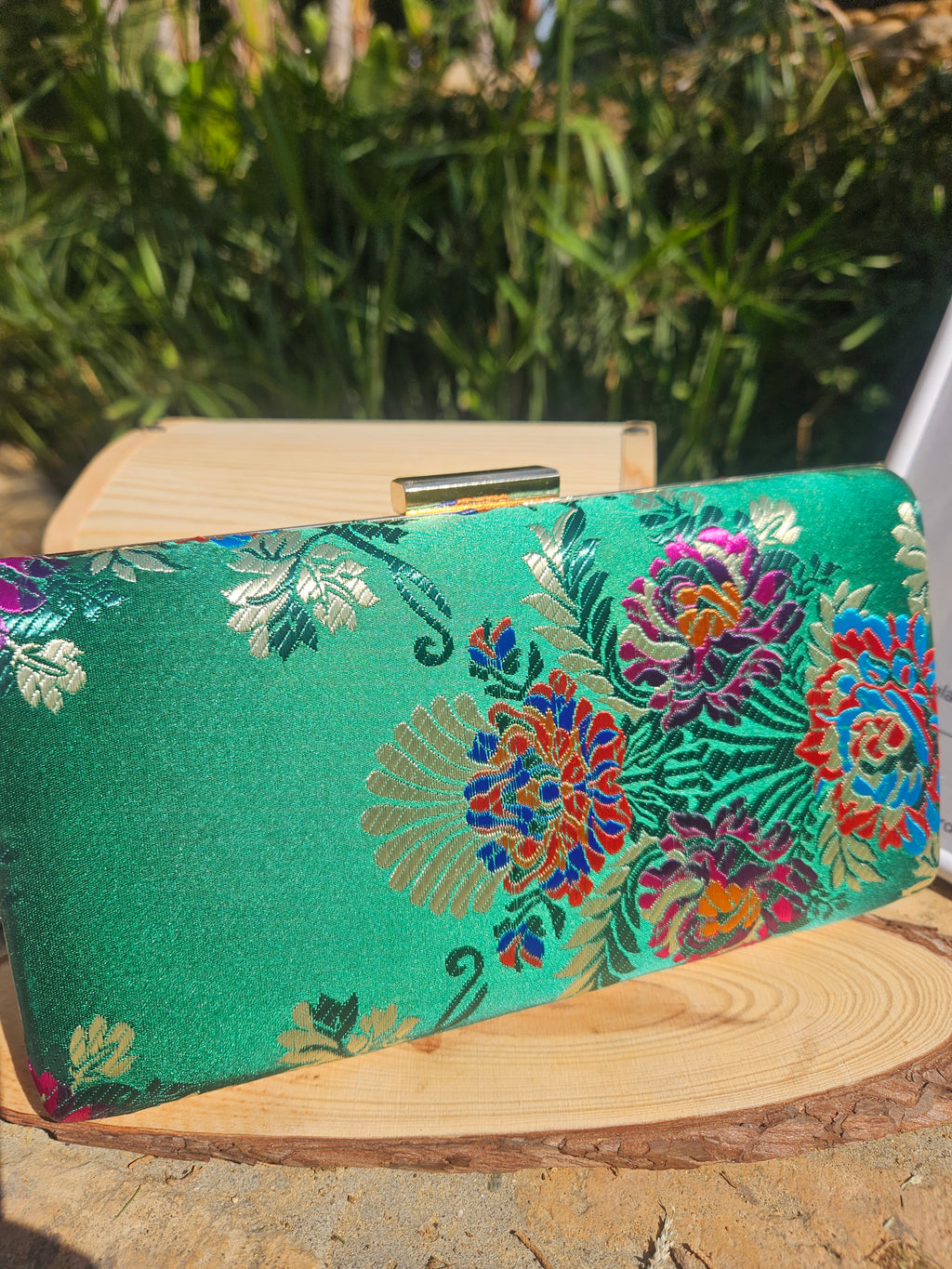Bolso de mano verde con flores bordadas multicolor y marco de madera, vista lateral