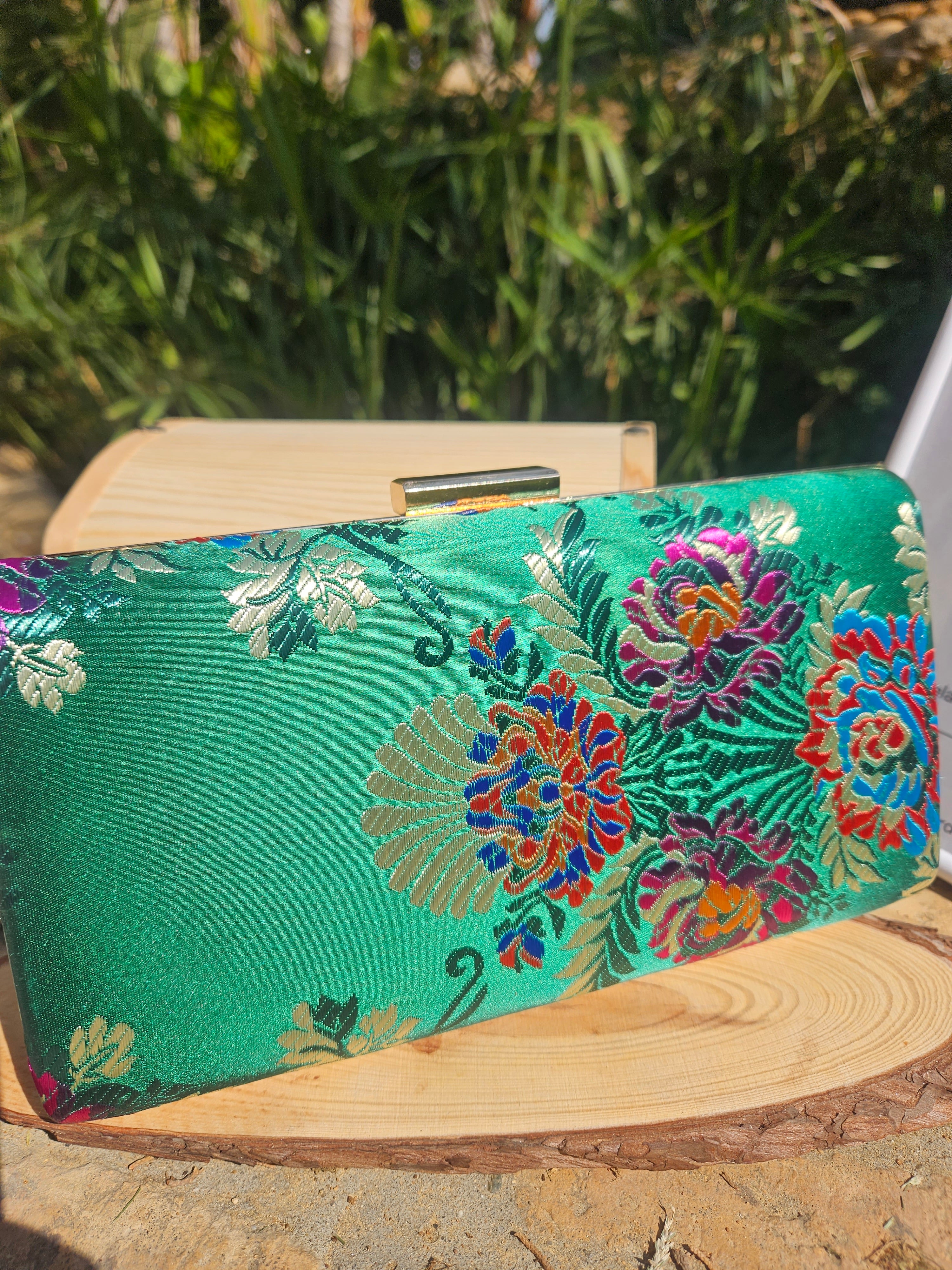 Bolso de mano verde con flores bordadas multicolor y marco de madera, vista lateral