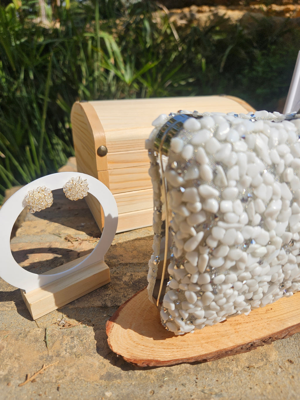 Bolso Islandia con abalorios blancos y correa metálica plateada sobre base de madera