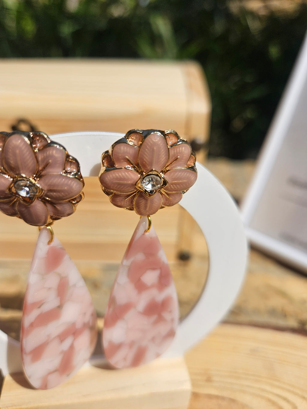 Pendientes con flores doradas y colgantes tipo gota rosa con vetas claras.