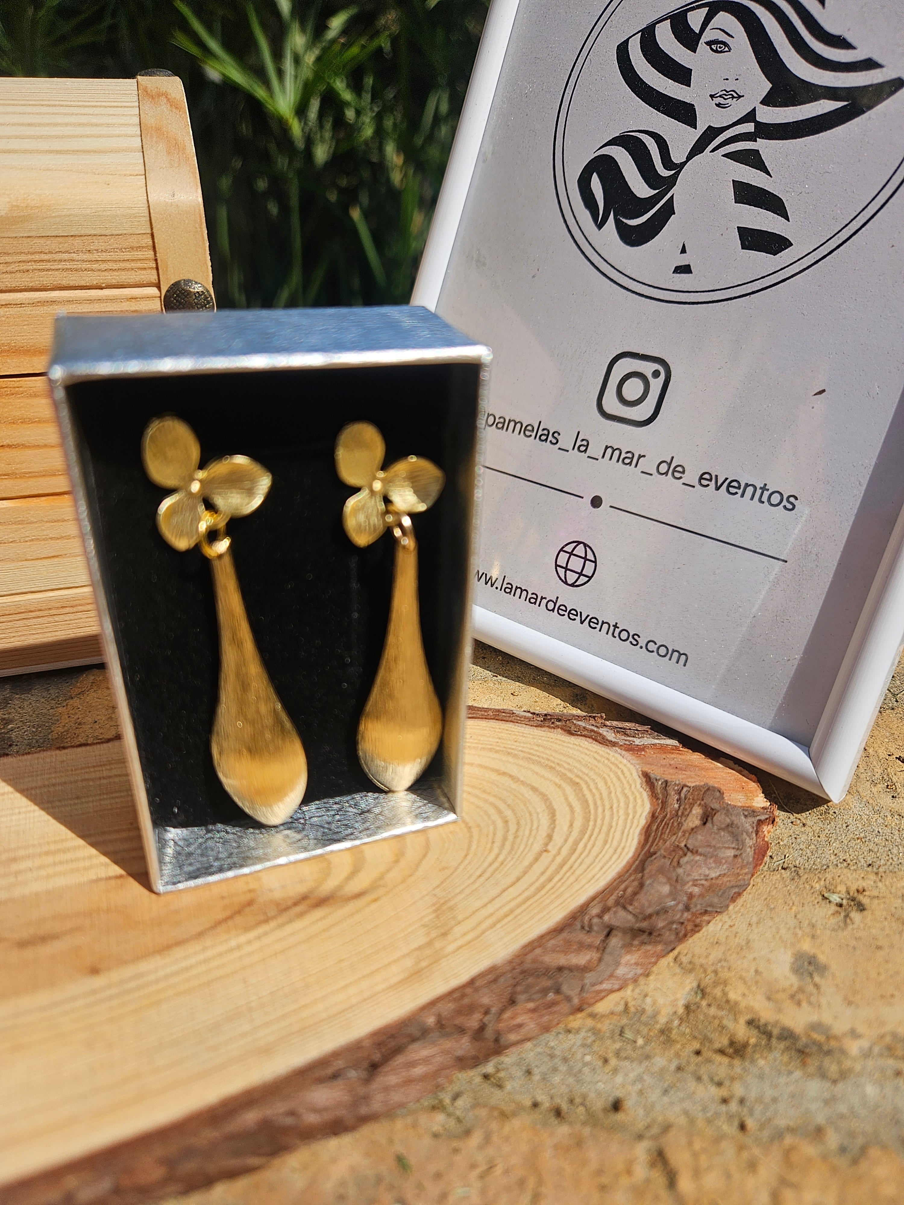Pendientes dorados flor con colgantes tipo gota, en caja sobre base de madera