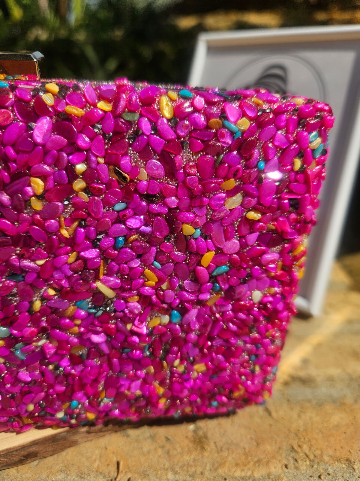 Bolso de pedrería magenta brillante con destellos dorados y turquesa, primer plano