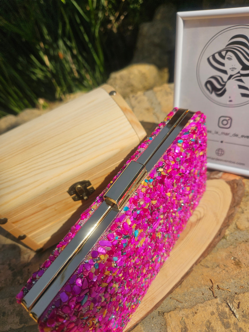 Bolso tipo cartera de madera con cierre metálico y pedrería rosa, vista lateral