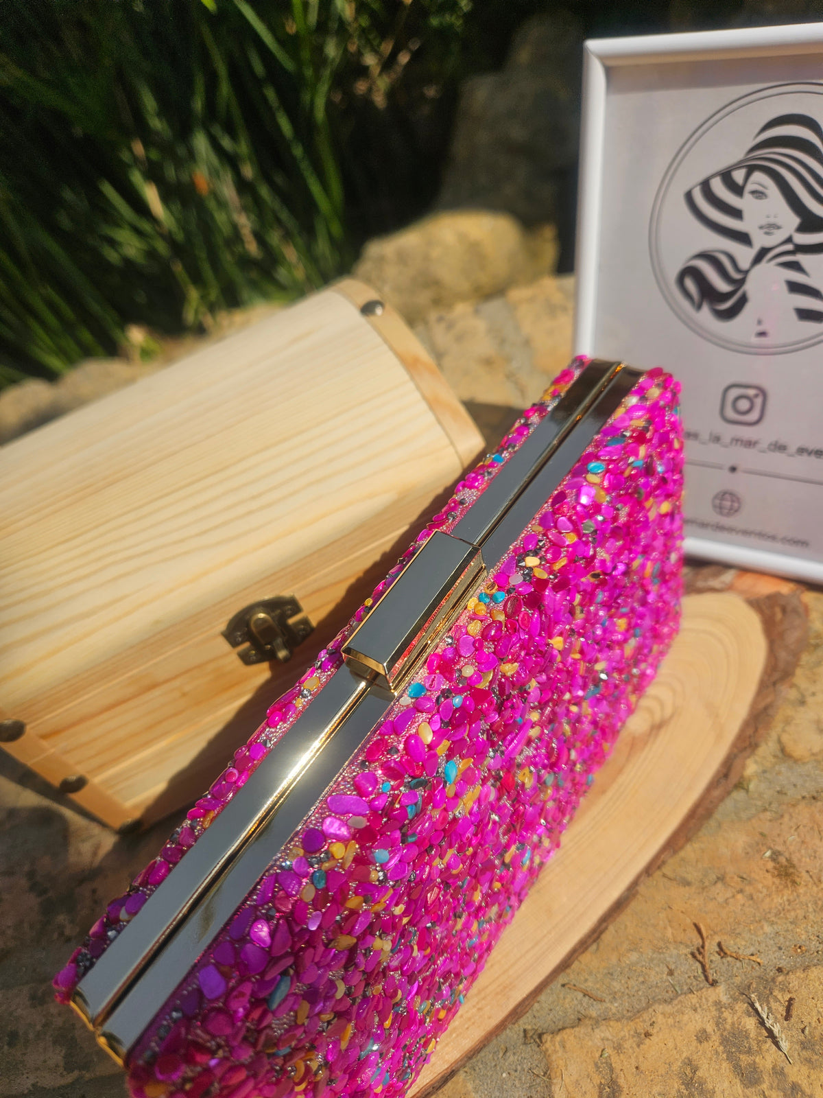 Bolso tipo cartera de madera con cierre metálico y pedrería rosa, vista lateral