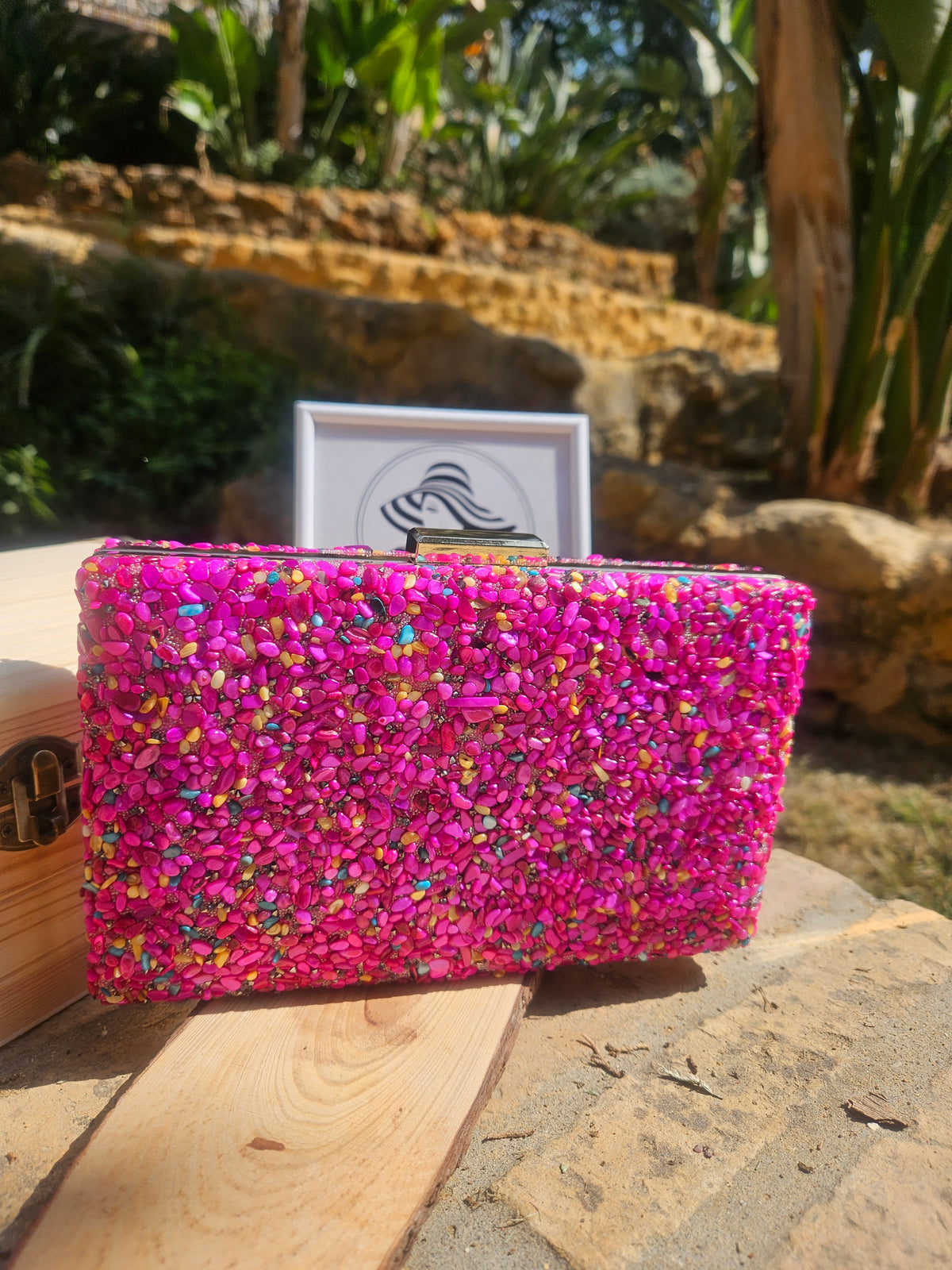 Bolso rectangular de pedrería rosa con reflejos multicolor y asa metálica superior