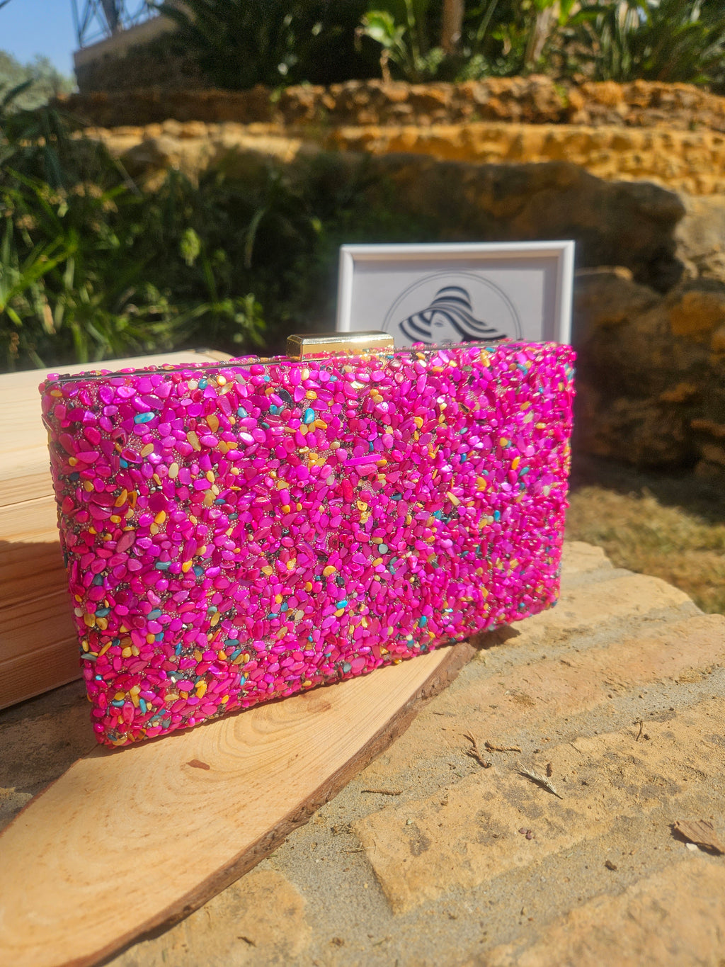 Bolso rectangular de pedrería fucsia con bordes de madera clara, vista lateral