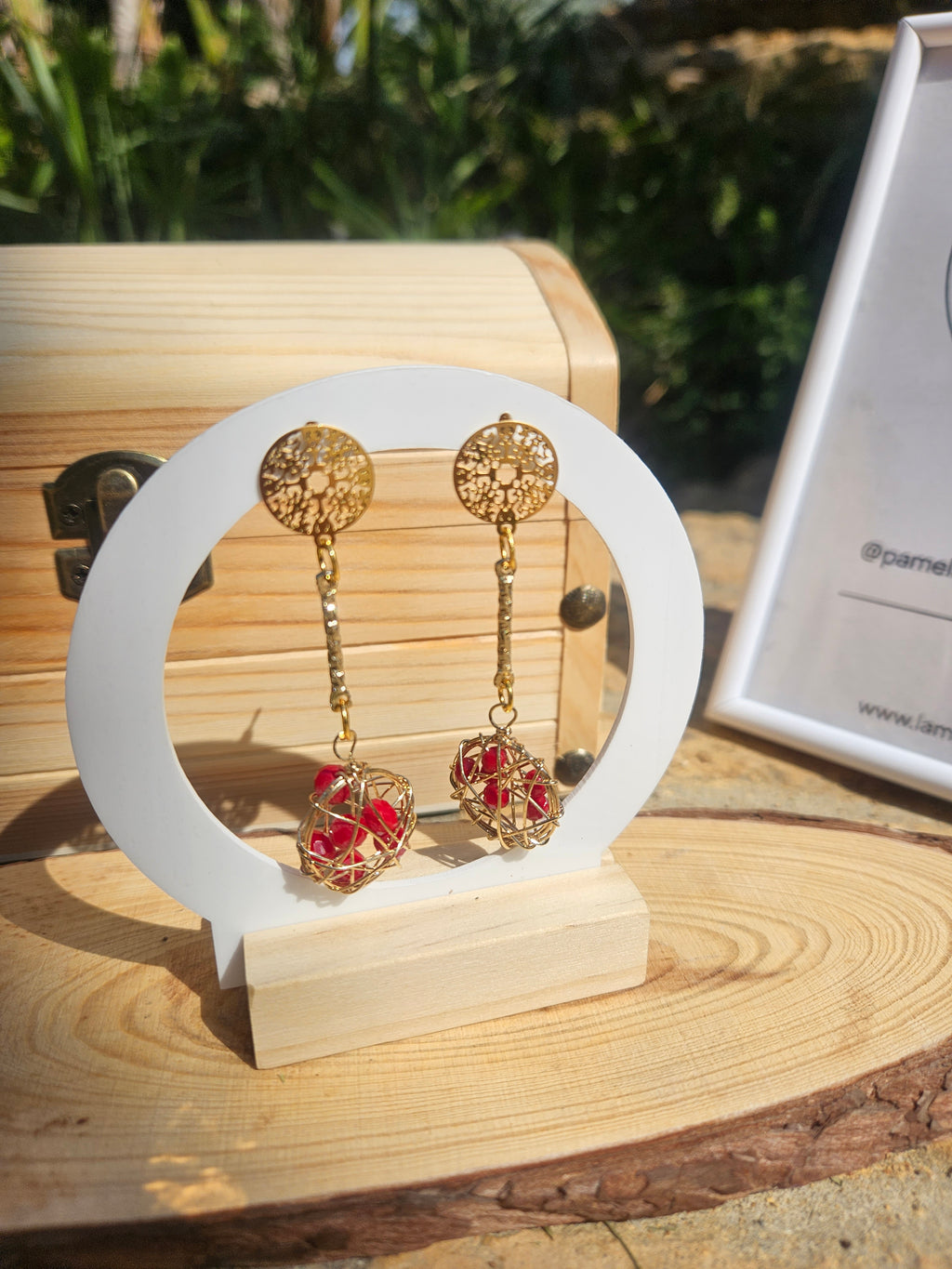 Pendientes colgantes con discos dorados y esfera roja de malla metálica.