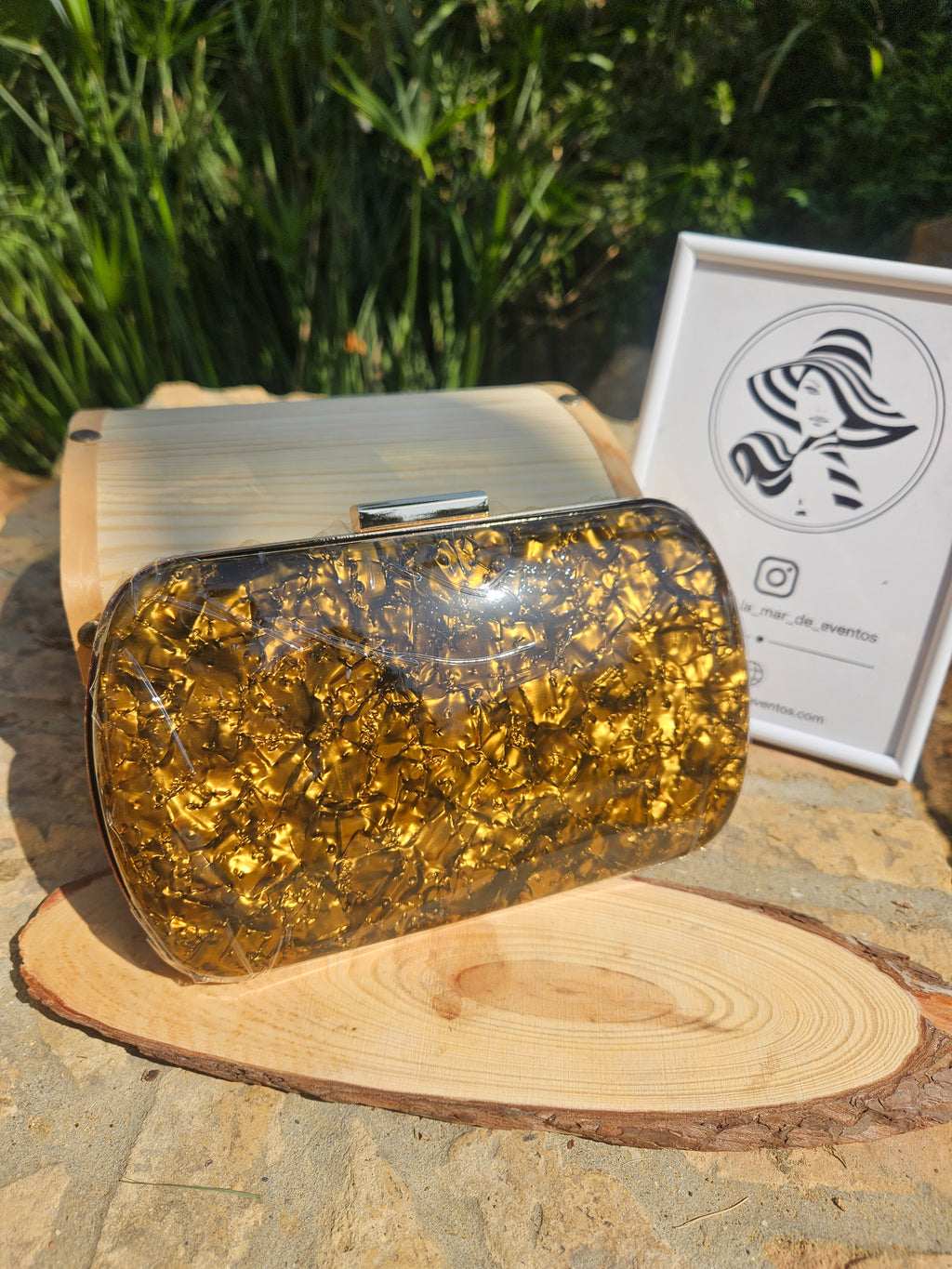 Bolso de mano dorado brillante con cierre metálico superior y forma ovalada