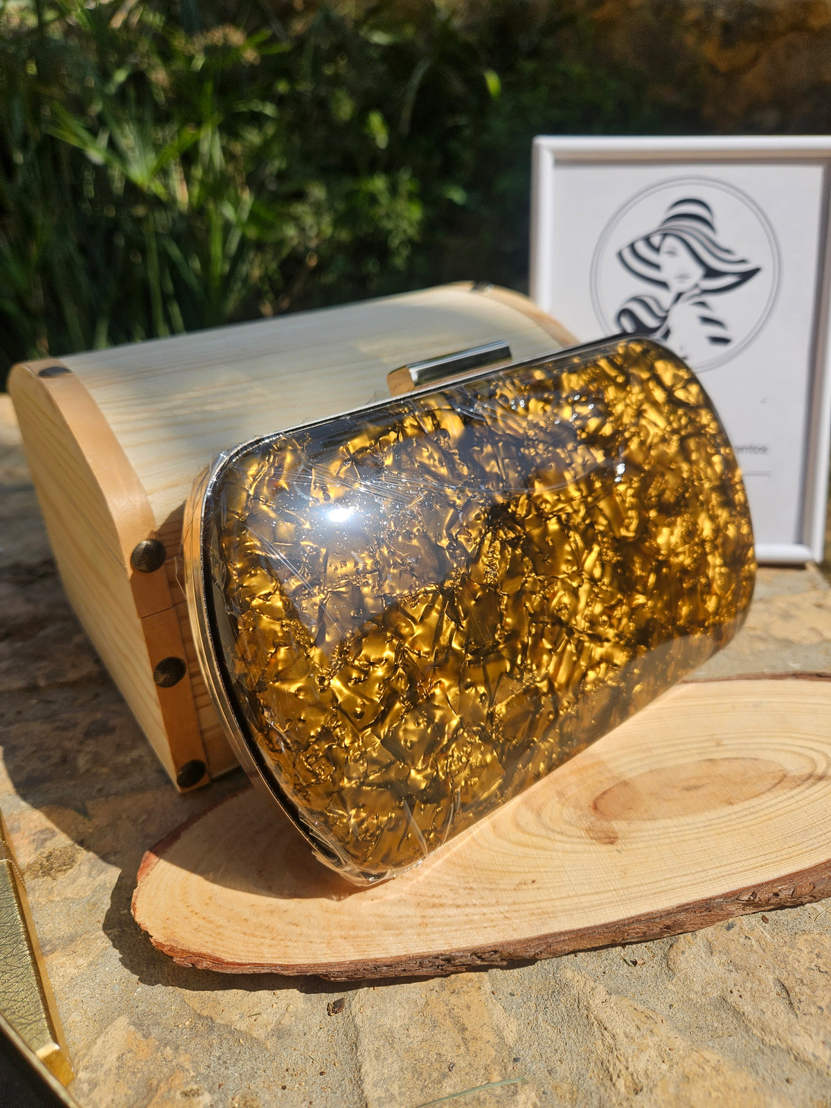 Bolso de mano dorado con brillo y asa superior, cierre metálico, acabado traslúcido