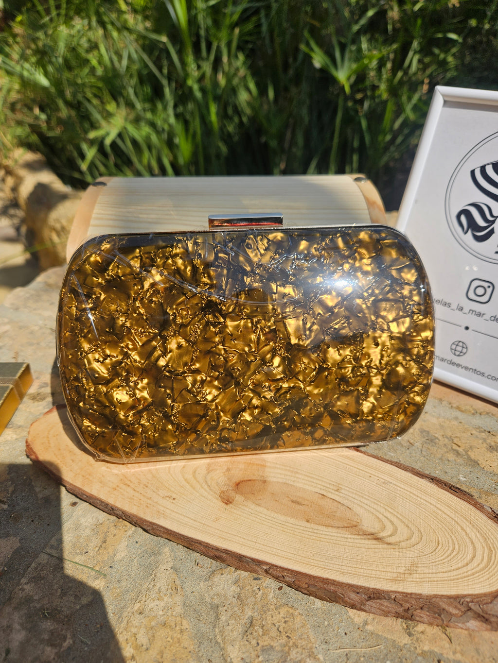 Bolso de mano dorado brillante con tapa superior transparente y cierre metálico