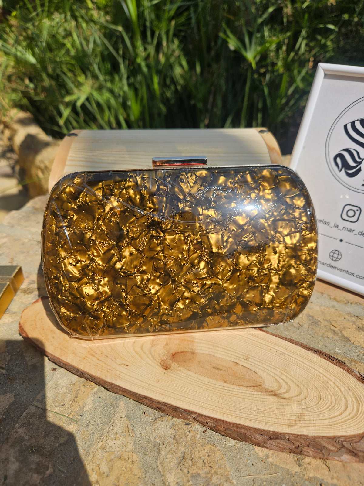 Bolso de mano dorado brillante con tapa superior transparente y cierre metálico