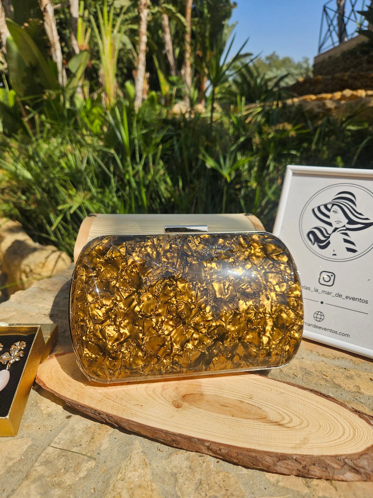 Bolso de mano dorado brillante con tapa superior y cierre metálico rectangular