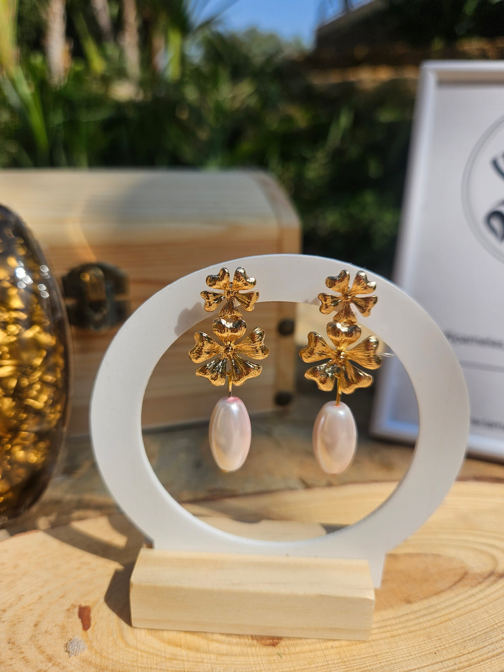 Pendientes dorados con flores y colgantes perlados blancos, vista frontal