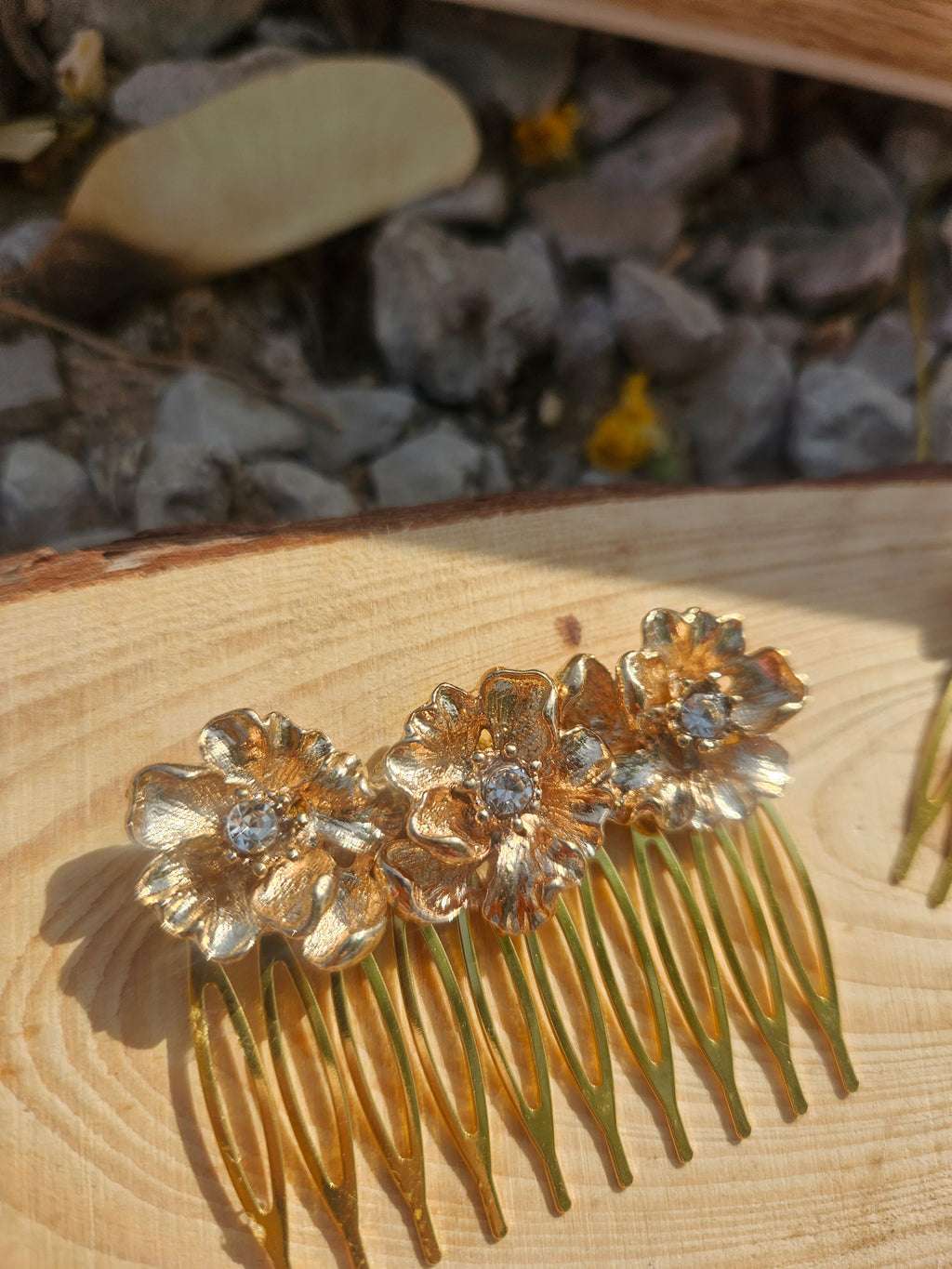 Peina dorada con flores y púas metálicas sobre base de madera