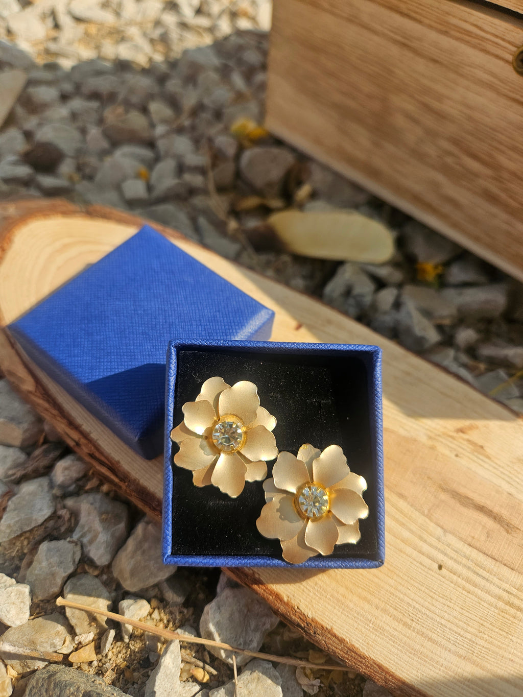 Pendientes Sam con flores doradas y pedrería central, en caja azul
