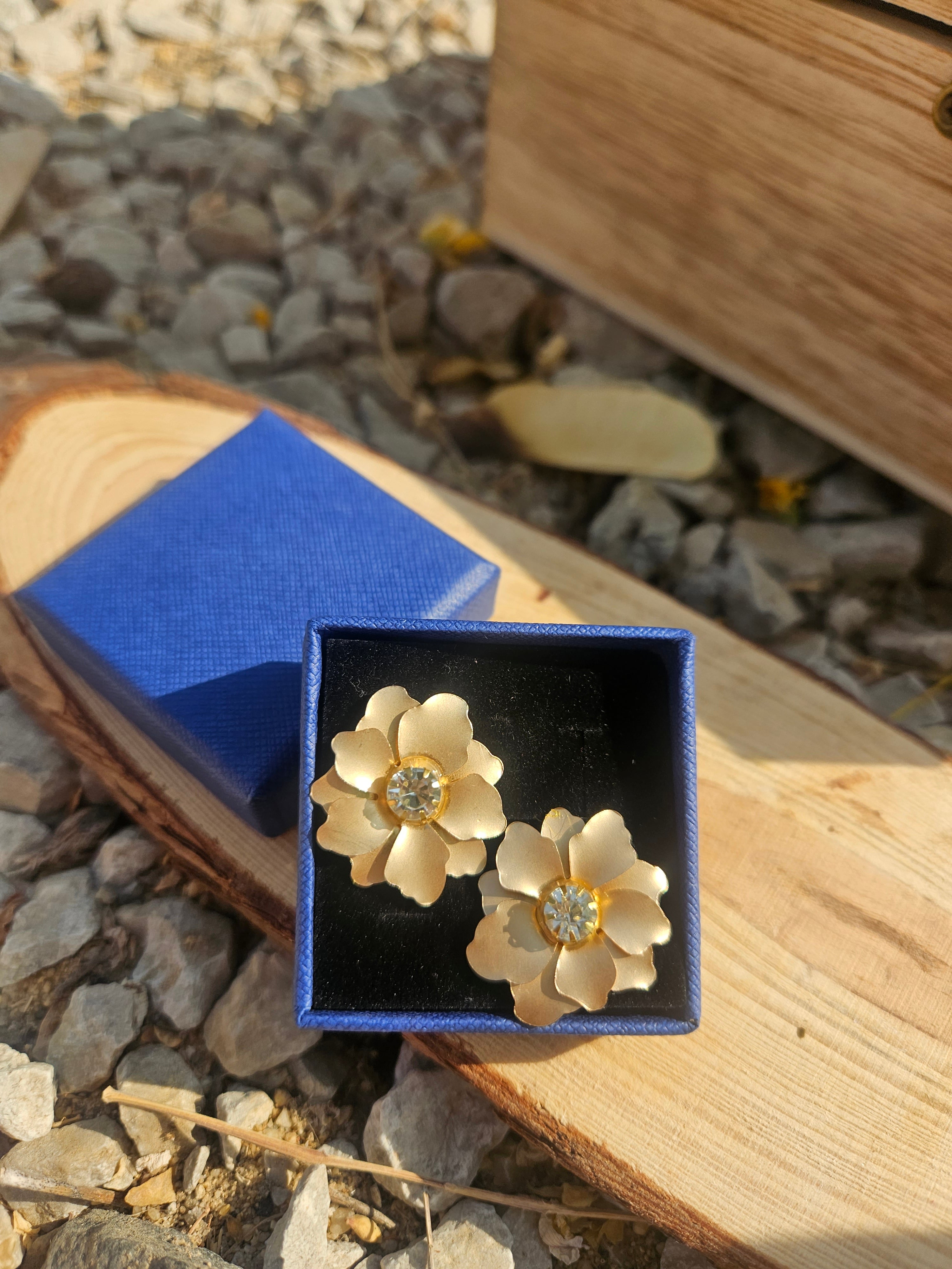 Pendientes Sam con flores doradas y pedrería central, en caja azul