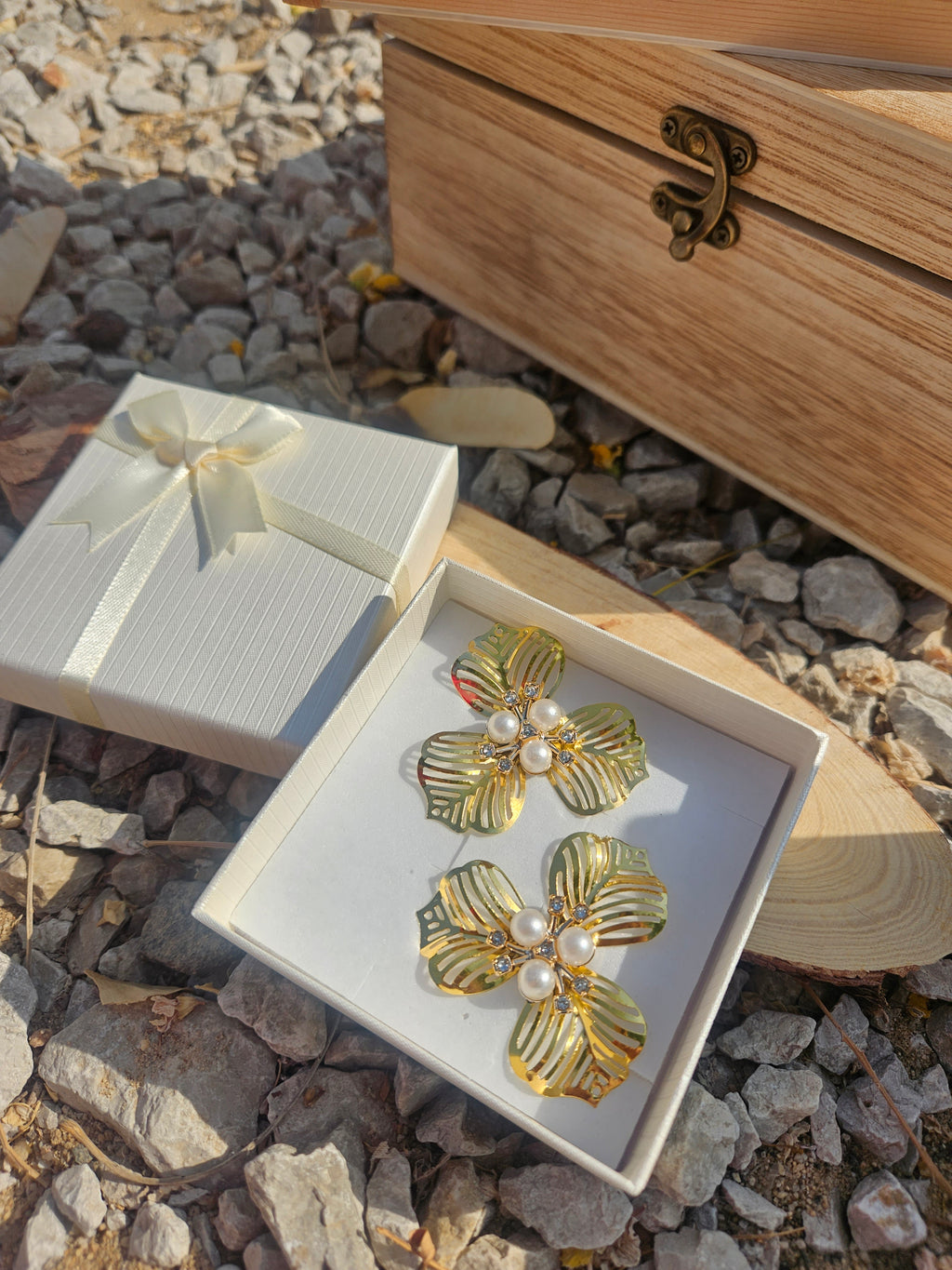 Pendientes dorados con motivos florales y perlas blancas en el centro