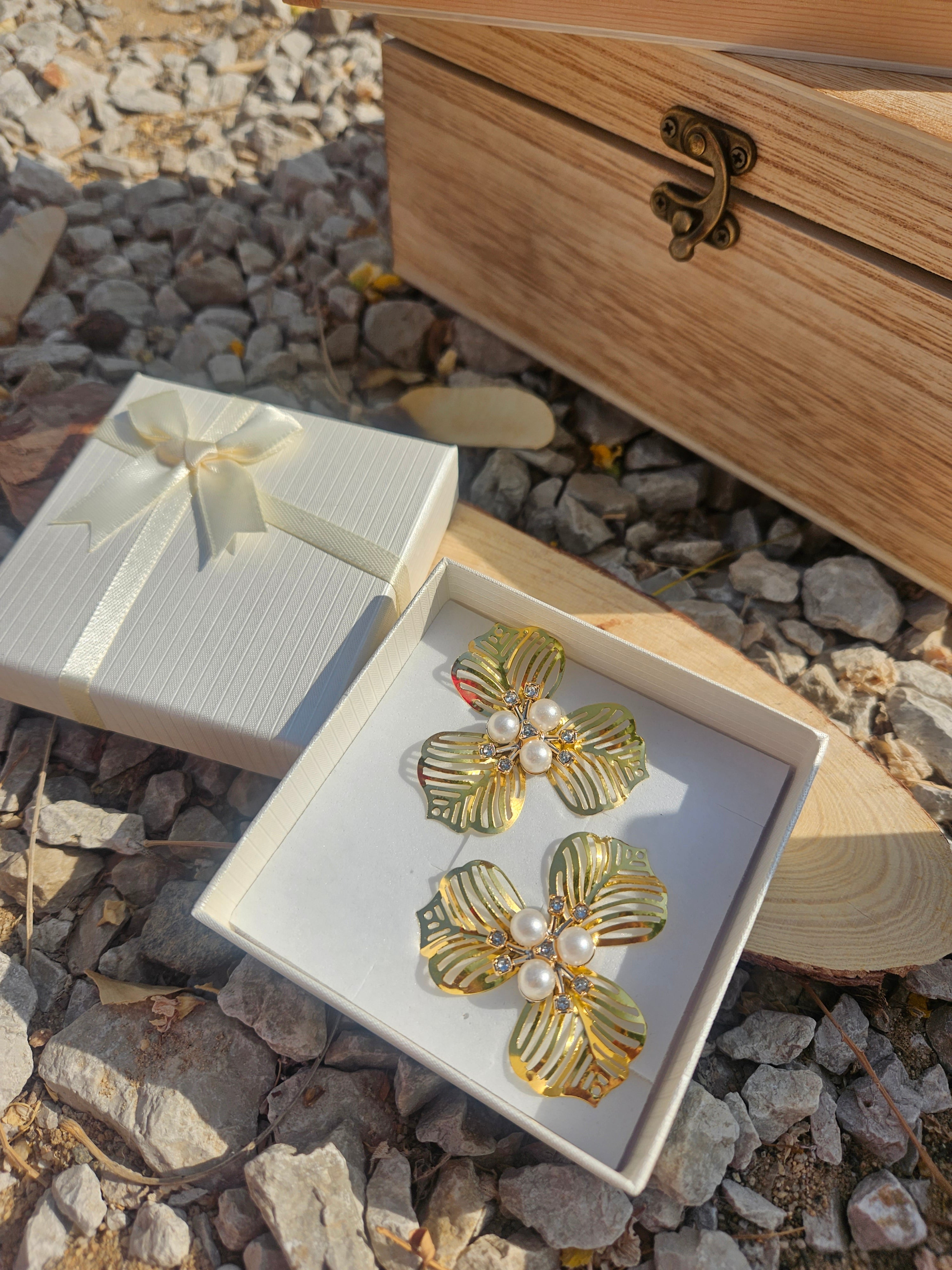 Pendientes dorados con motivos florales y perlas blancas en el centro