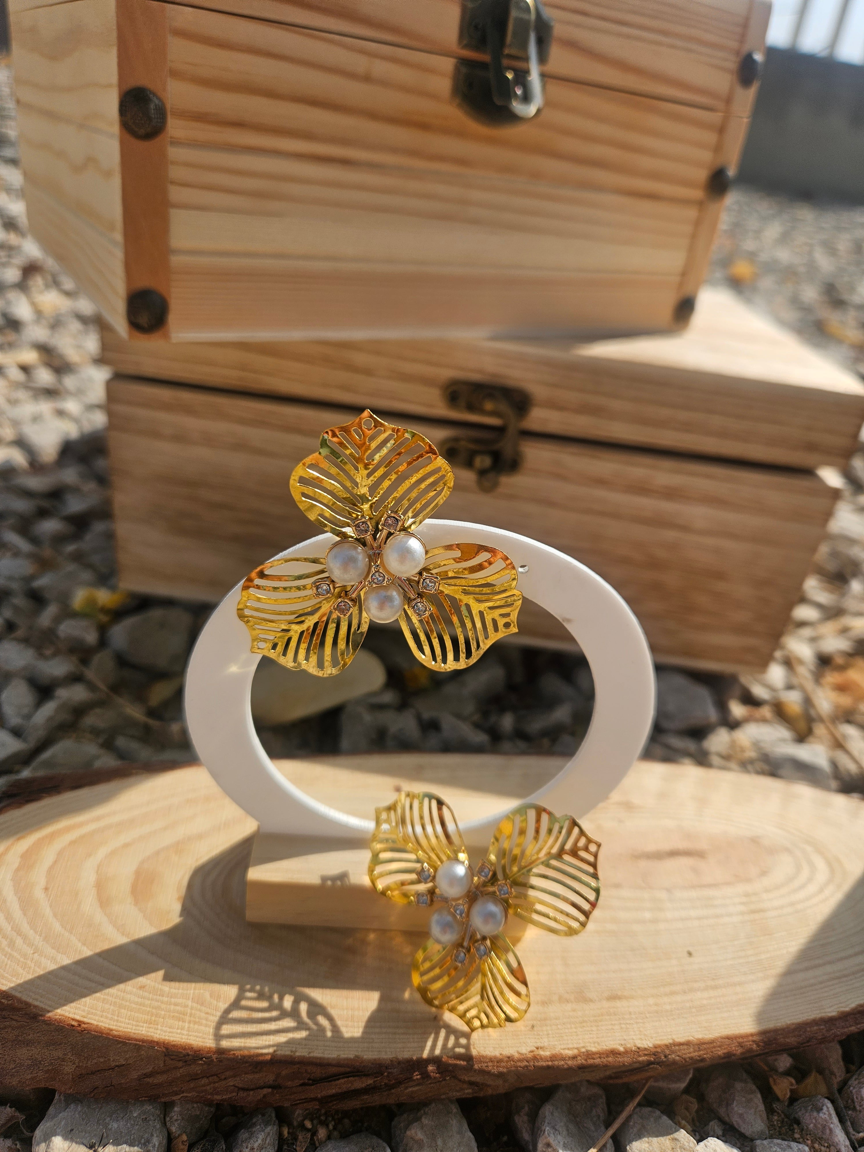 Pendientes flor dorada con nudos de perla blanca y diseño de hojas