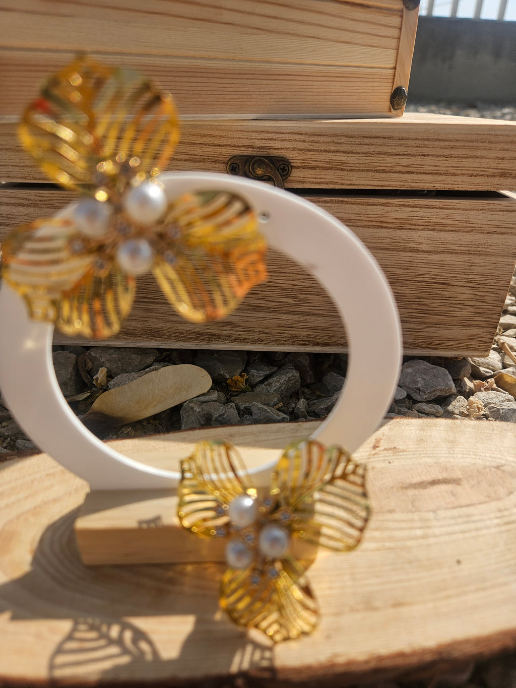 Pendientes dorados con flor de hojas y perlas blancas, vista cercana